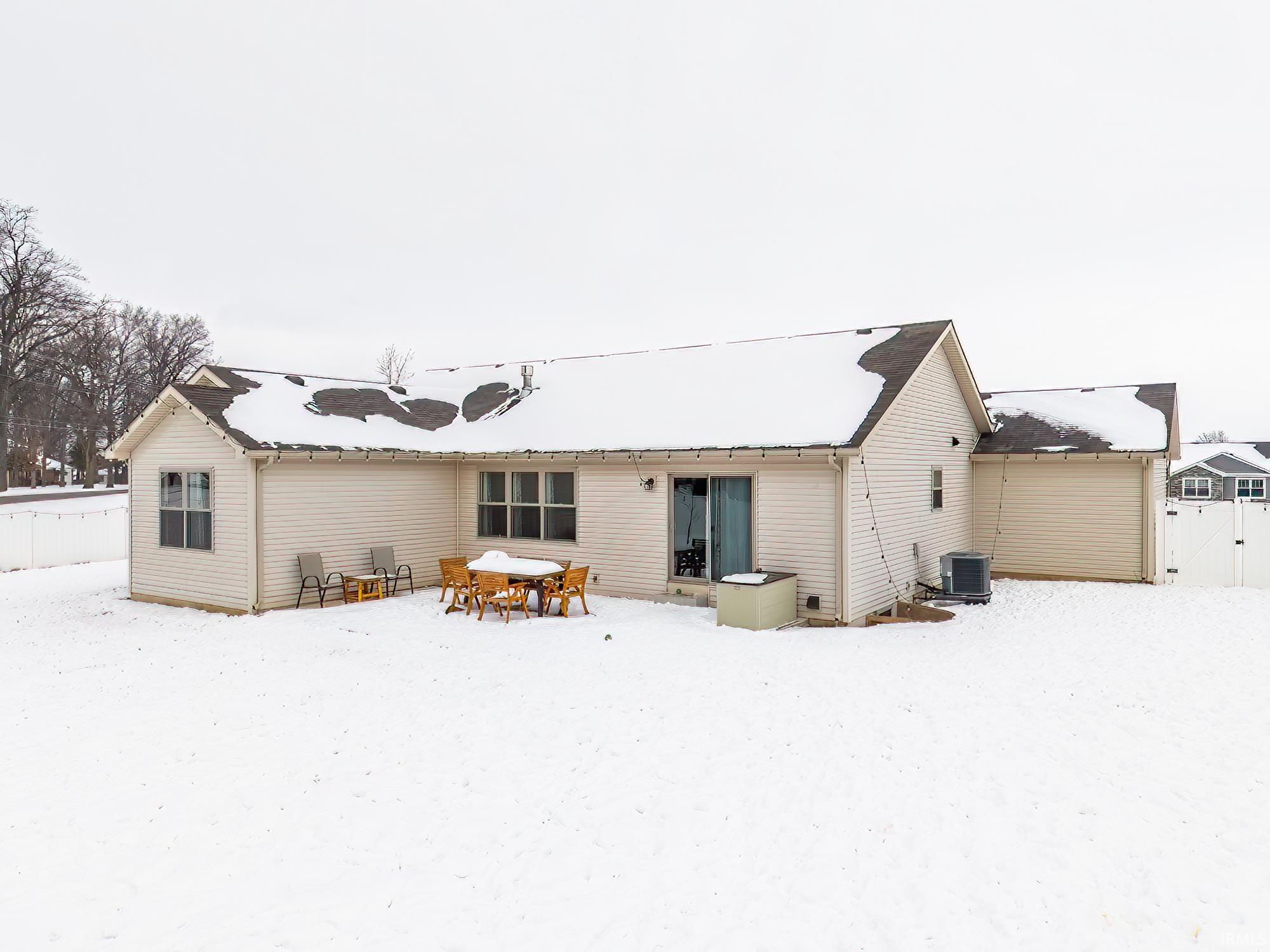 Snow covered rear of property featuring a gate and a patio
