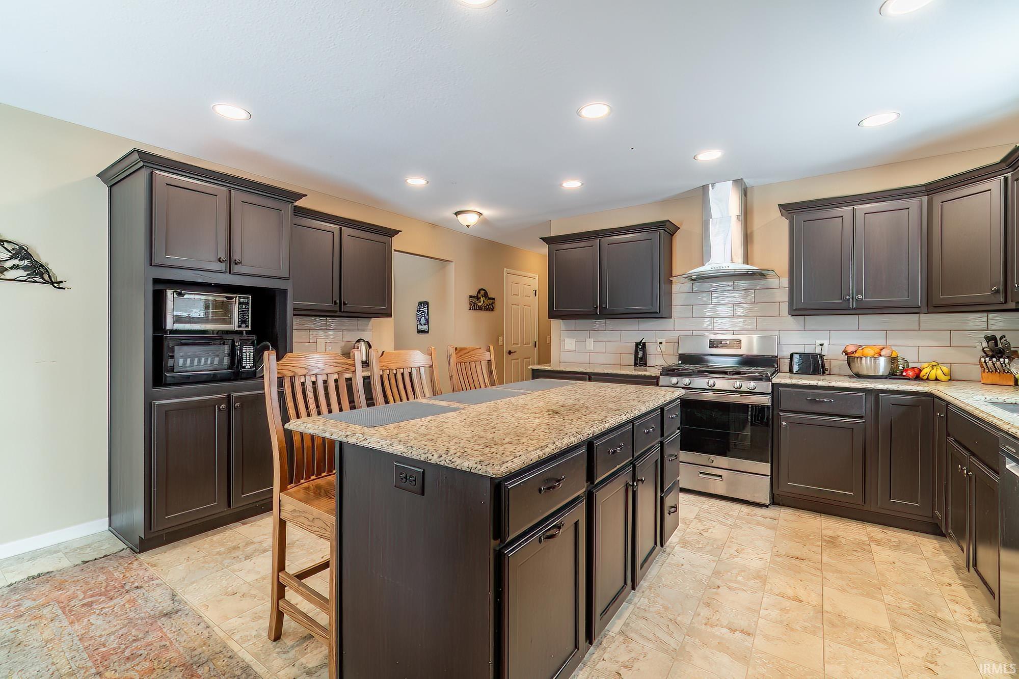 Kitchen featuring a kitchen breakfast bar, stainless steel appliances, a center island, light stone counters, and decorative backsplash