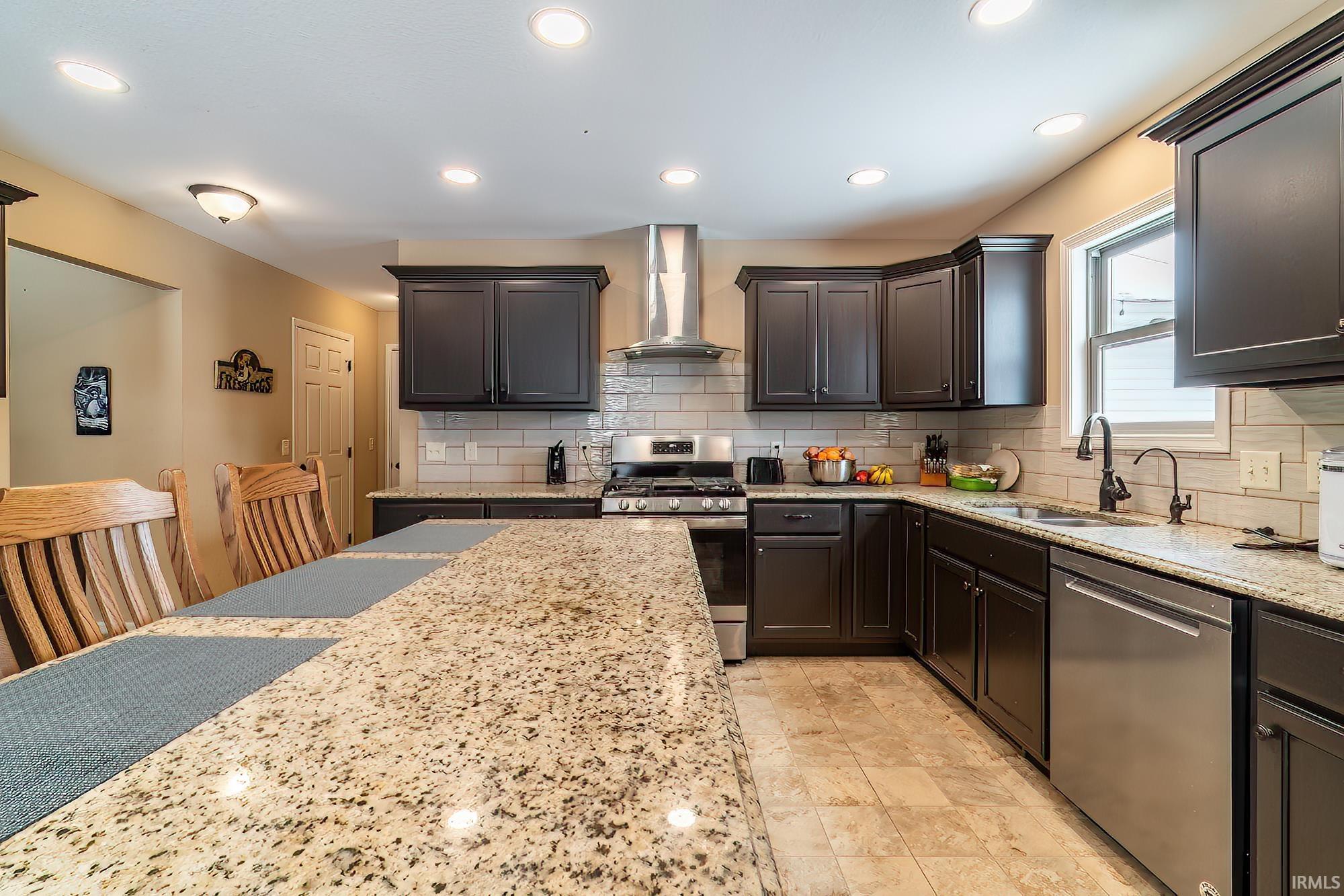 Kitchen featuring stainless steel appliances, light stone counters, recessed lighting, and tasteful backsplash