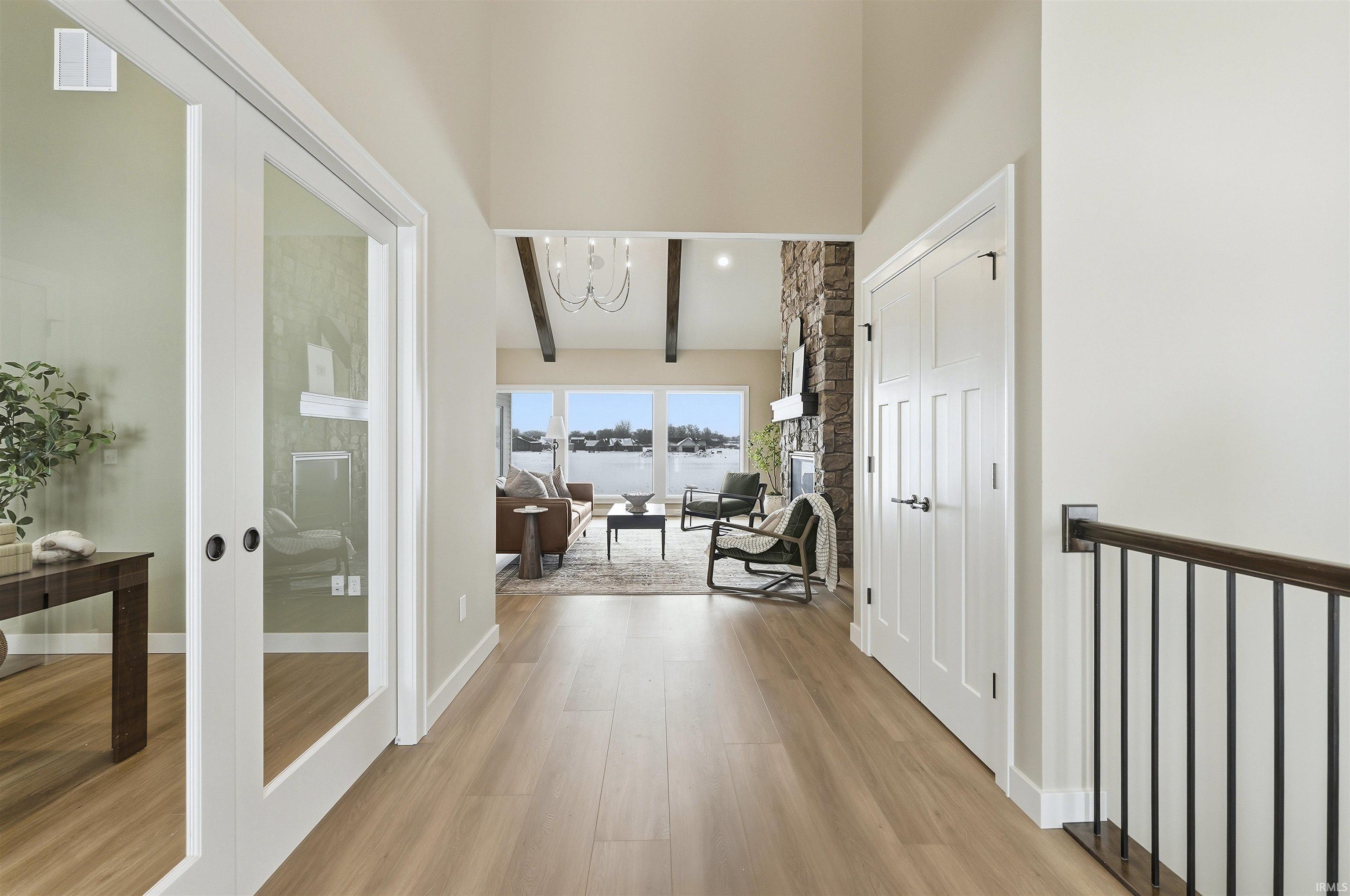 Hall with hanging lights, light wood-style flooring, french doors, and lofted ceiling