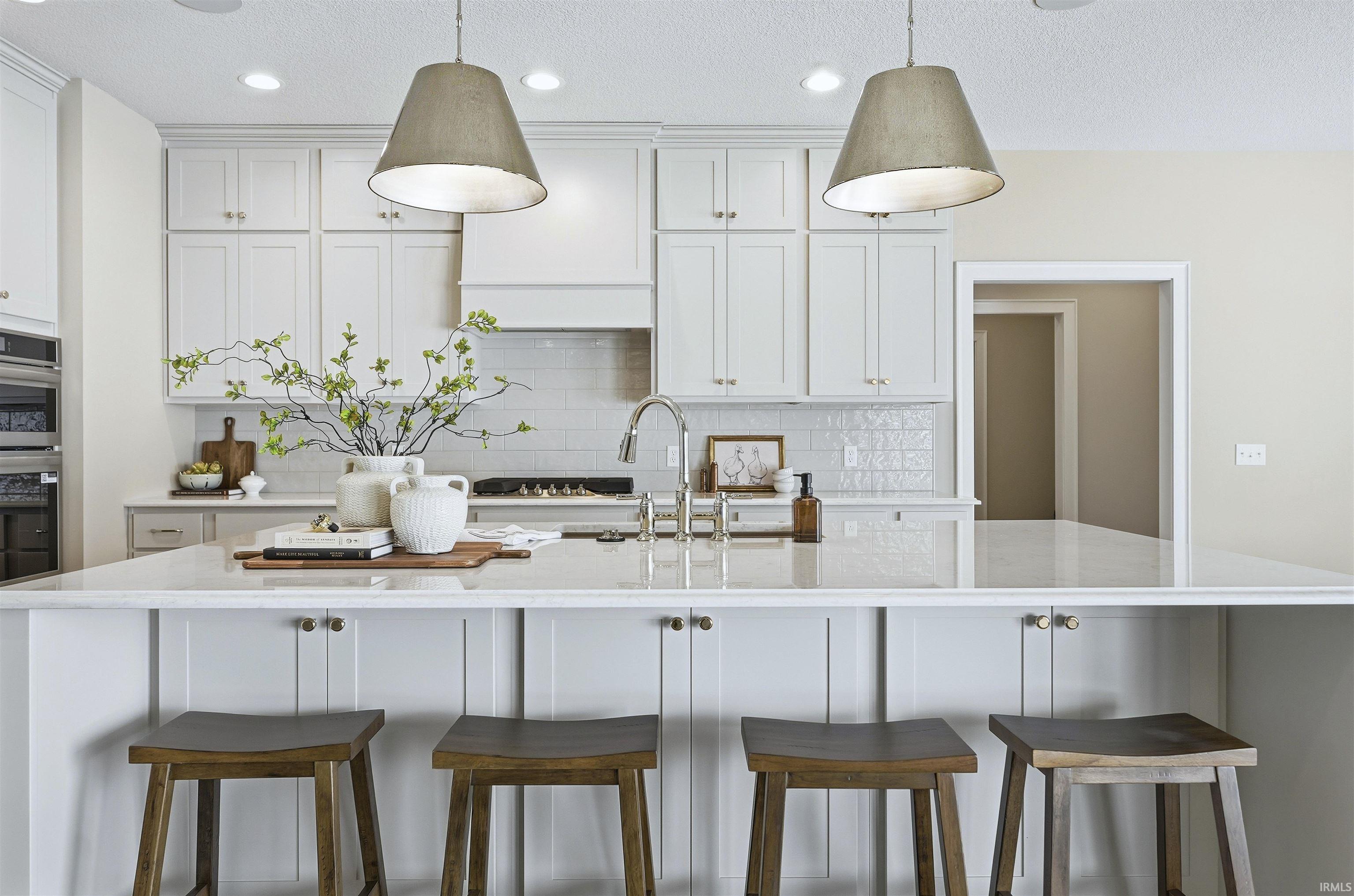 Kitchen with a breakfast bar area, white cabinets, a center island with sink, light stone countertops, and a textured ceiling