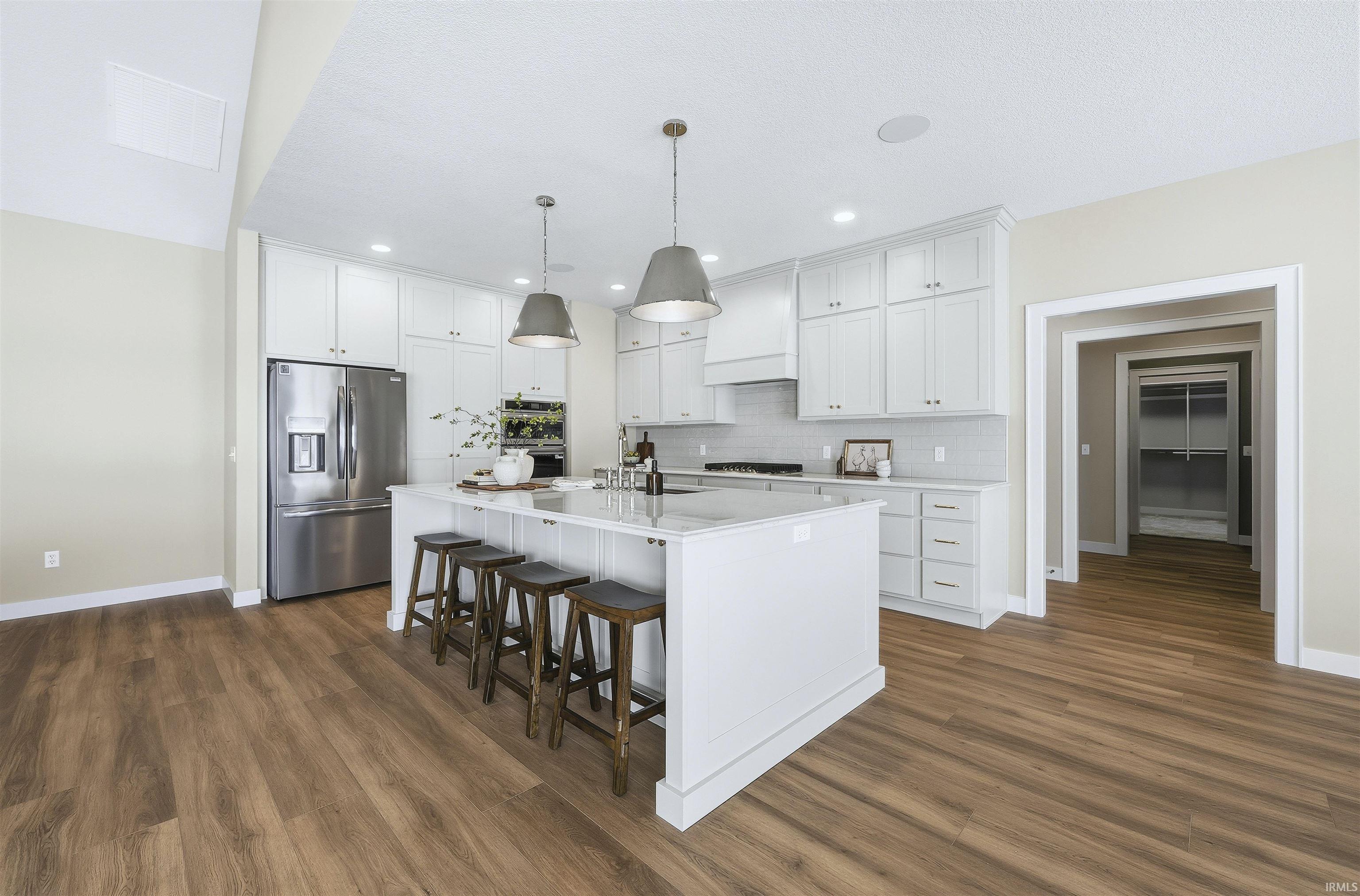 Kitchen with white cabinets, stainless steel appliances, a kitchen breakfast bar, and pendant lighting