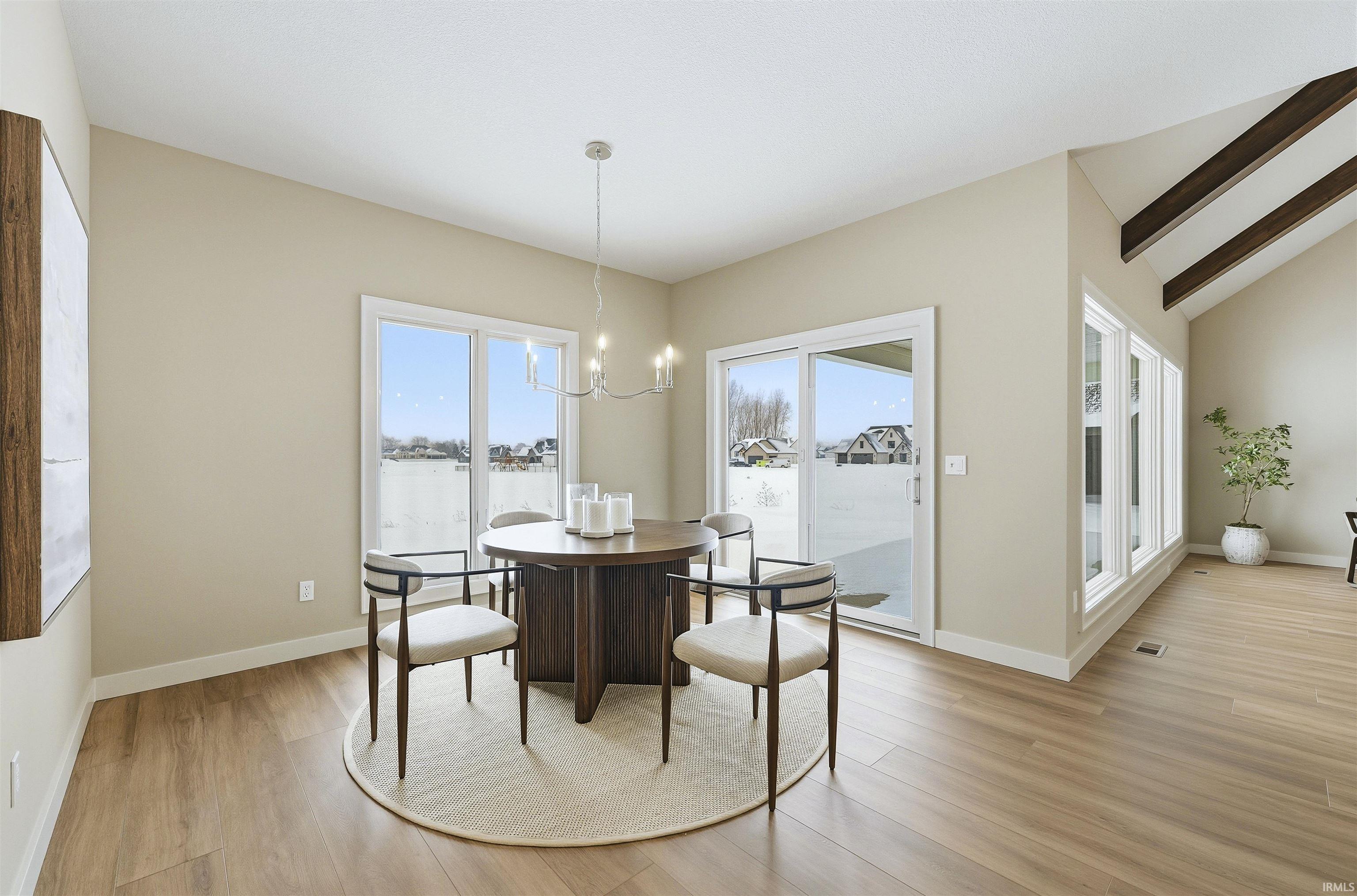 Dining area with light wood-type flooring, hanging lights, lofted ceiling, and healthy amount of natural light
