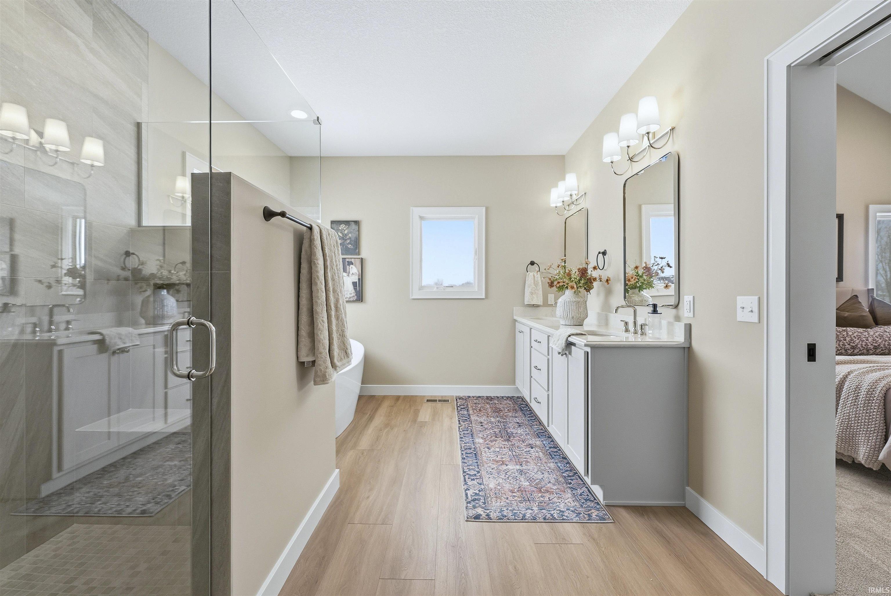 Bathroom featuring connected bathroom, double vanity, a stall shower, light wood finished floors, and a chandelier
