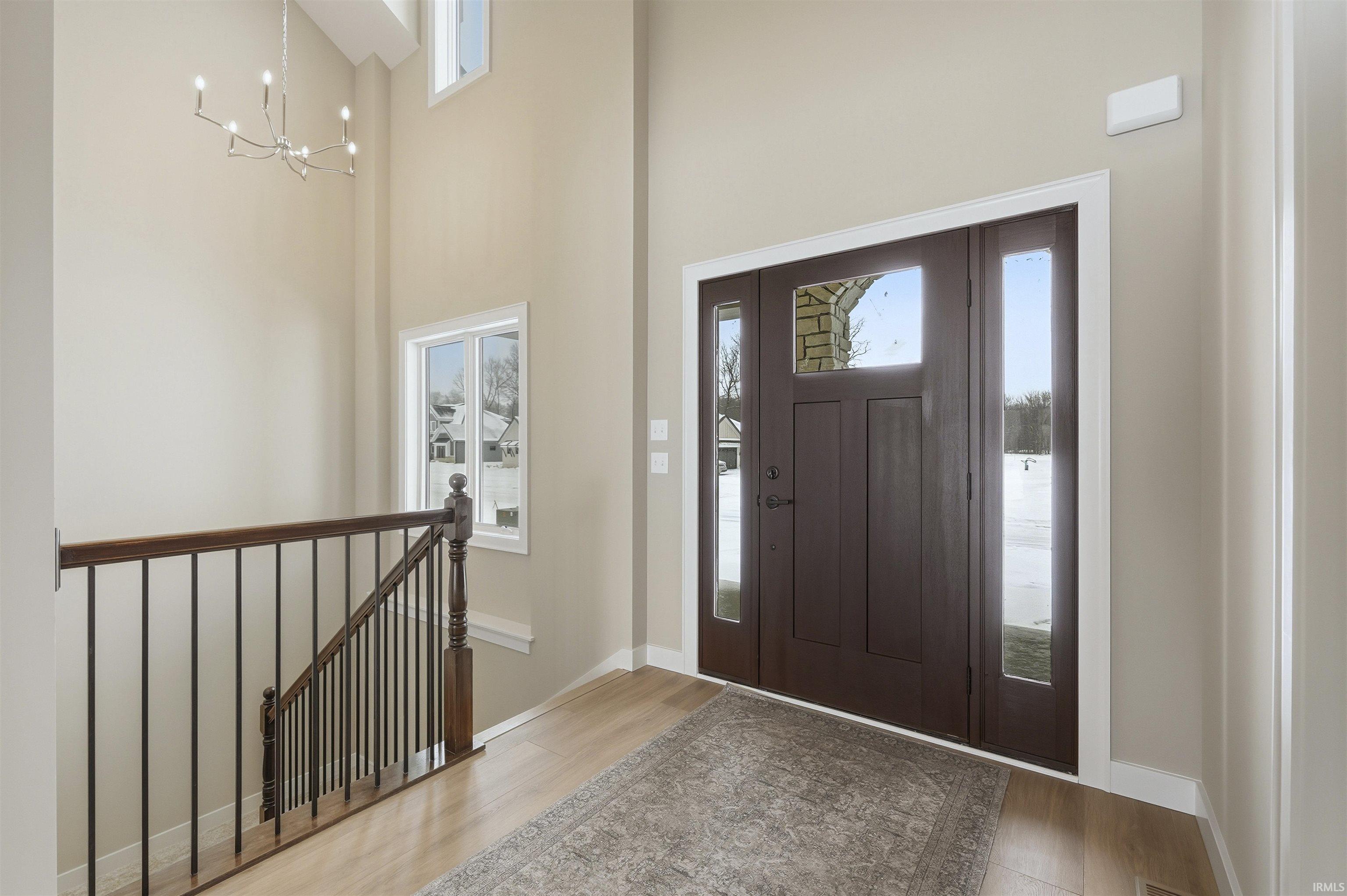 Entrance foyer featuring light wood finished floors, a chandelier, and a high ceiling
