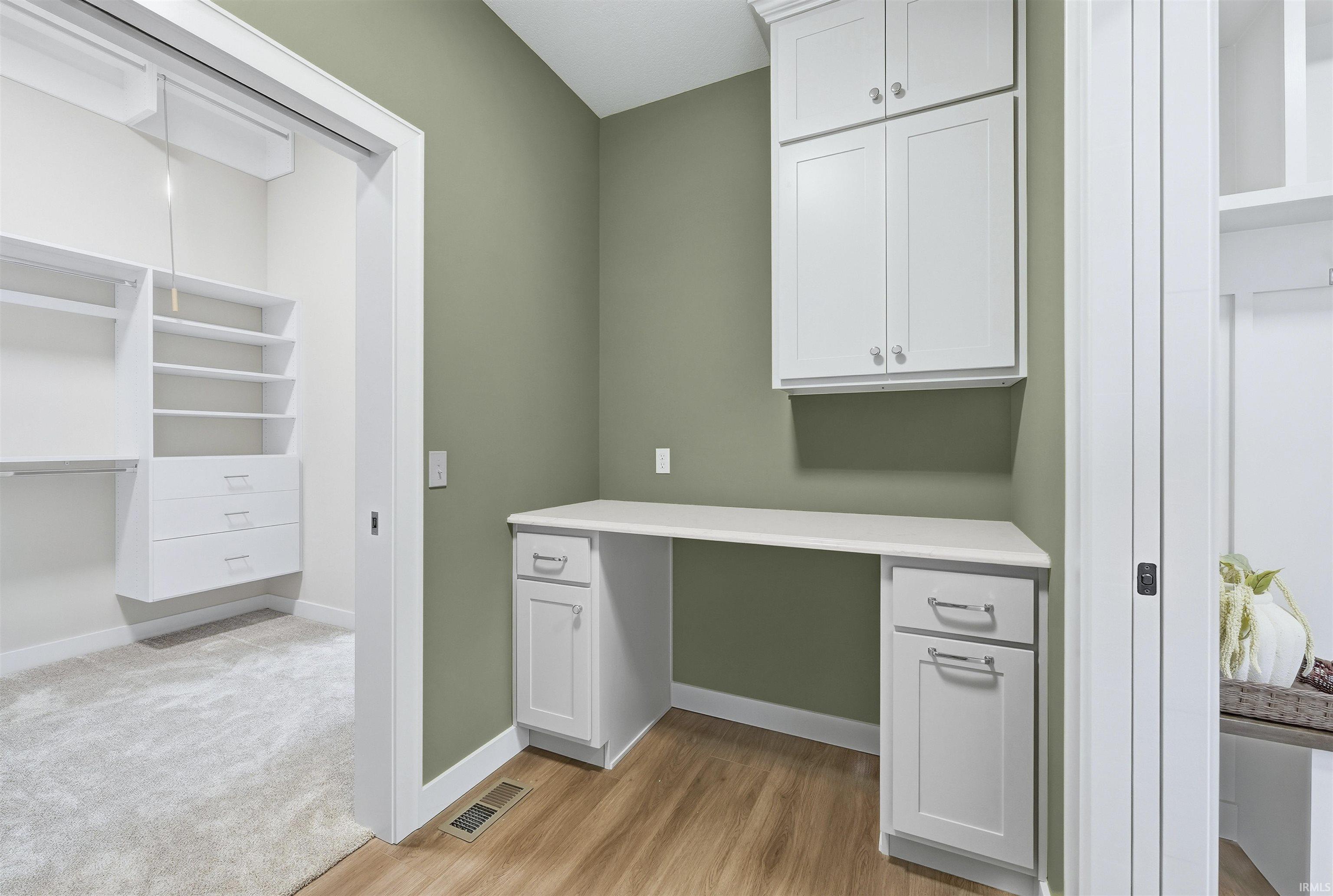 Unfurnished office with built in desk and light wood-style floors