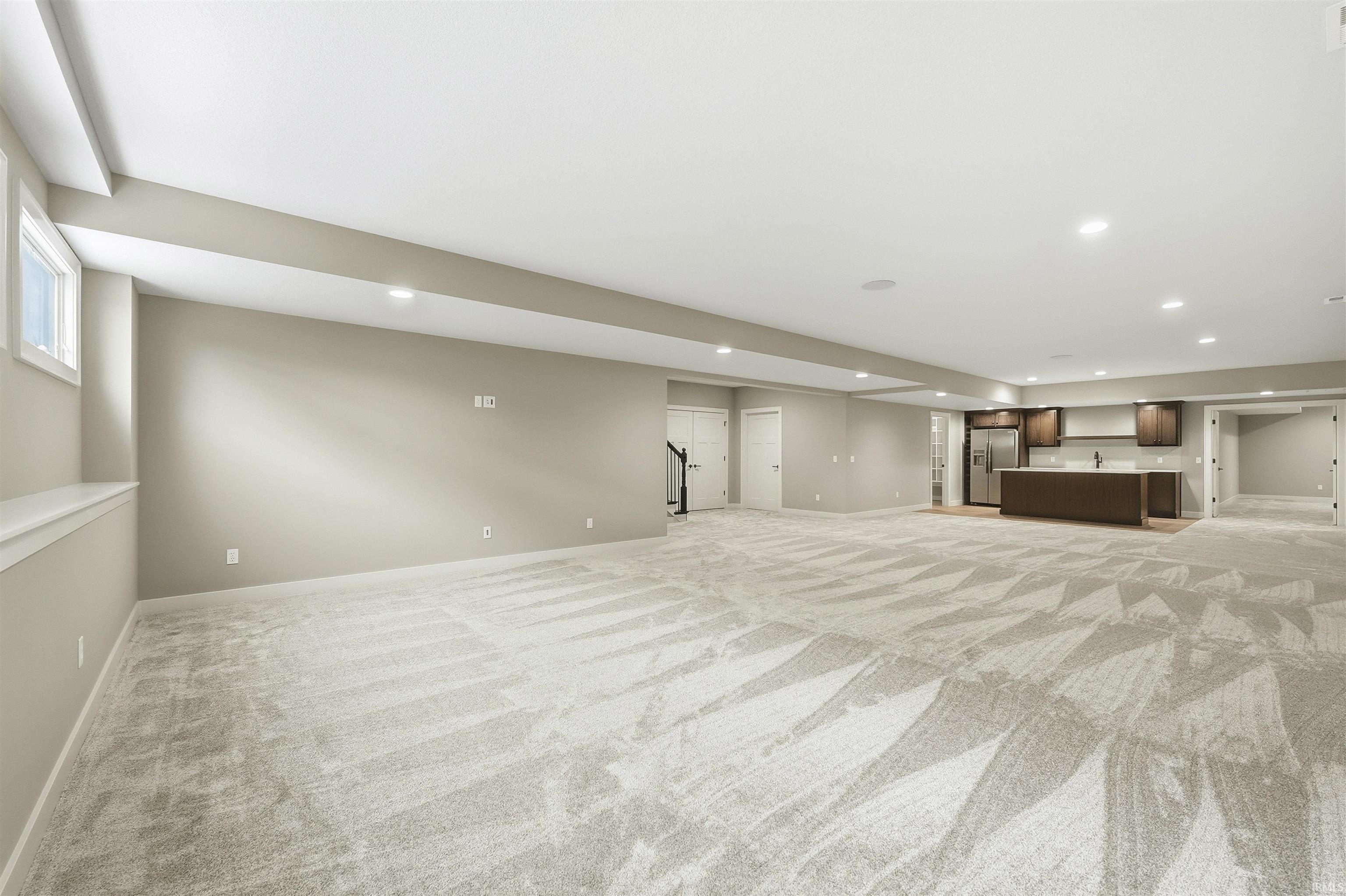 Below grade area with recessed lighting, light colored carpet, and stainless steel fridge