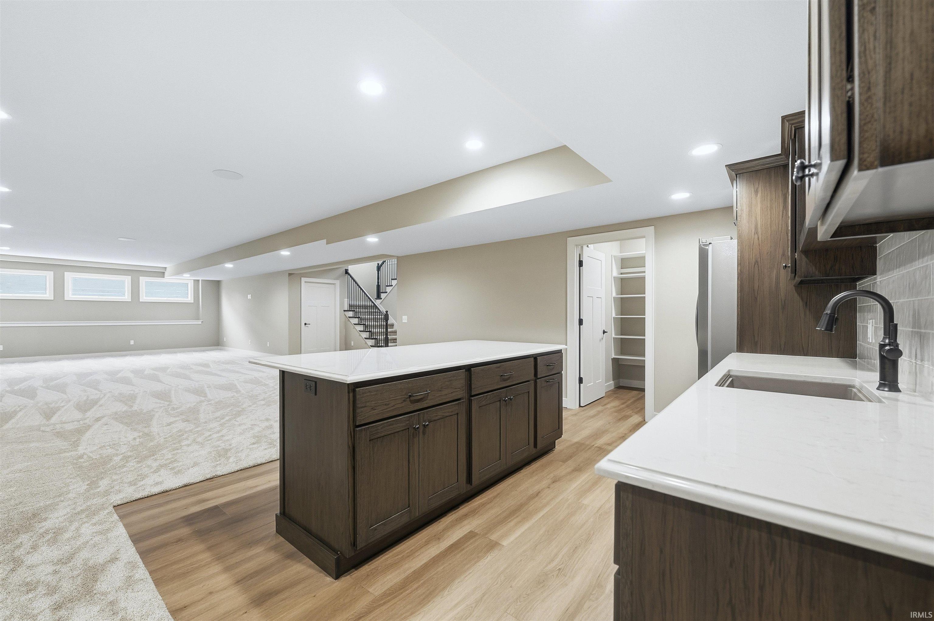 Kitchen with dark wood finish cabinetry, recessed lighting, open floor plan, a kitchen island, and light wood-style floors