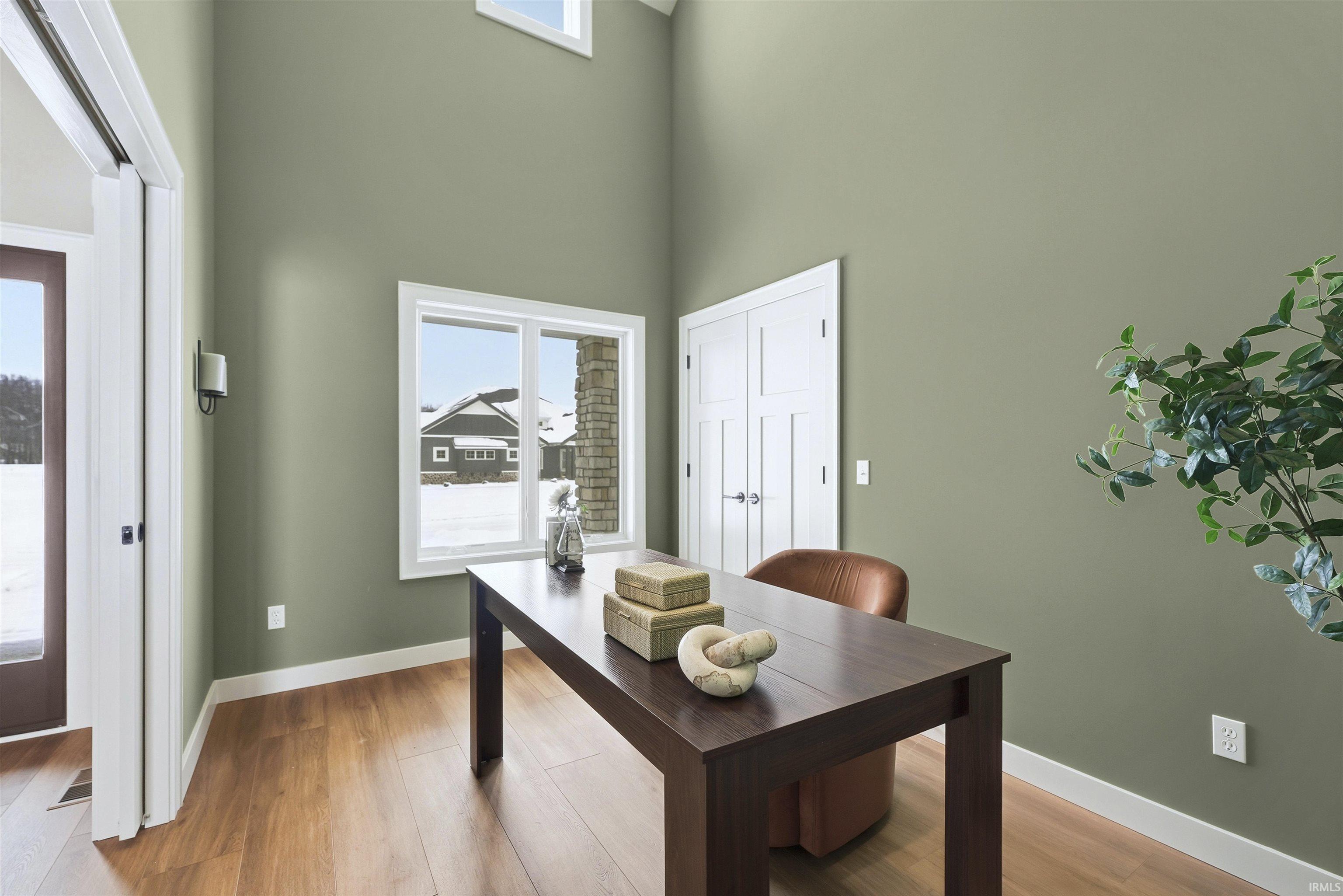 Office space with light wood finished floors and a high ceiling
