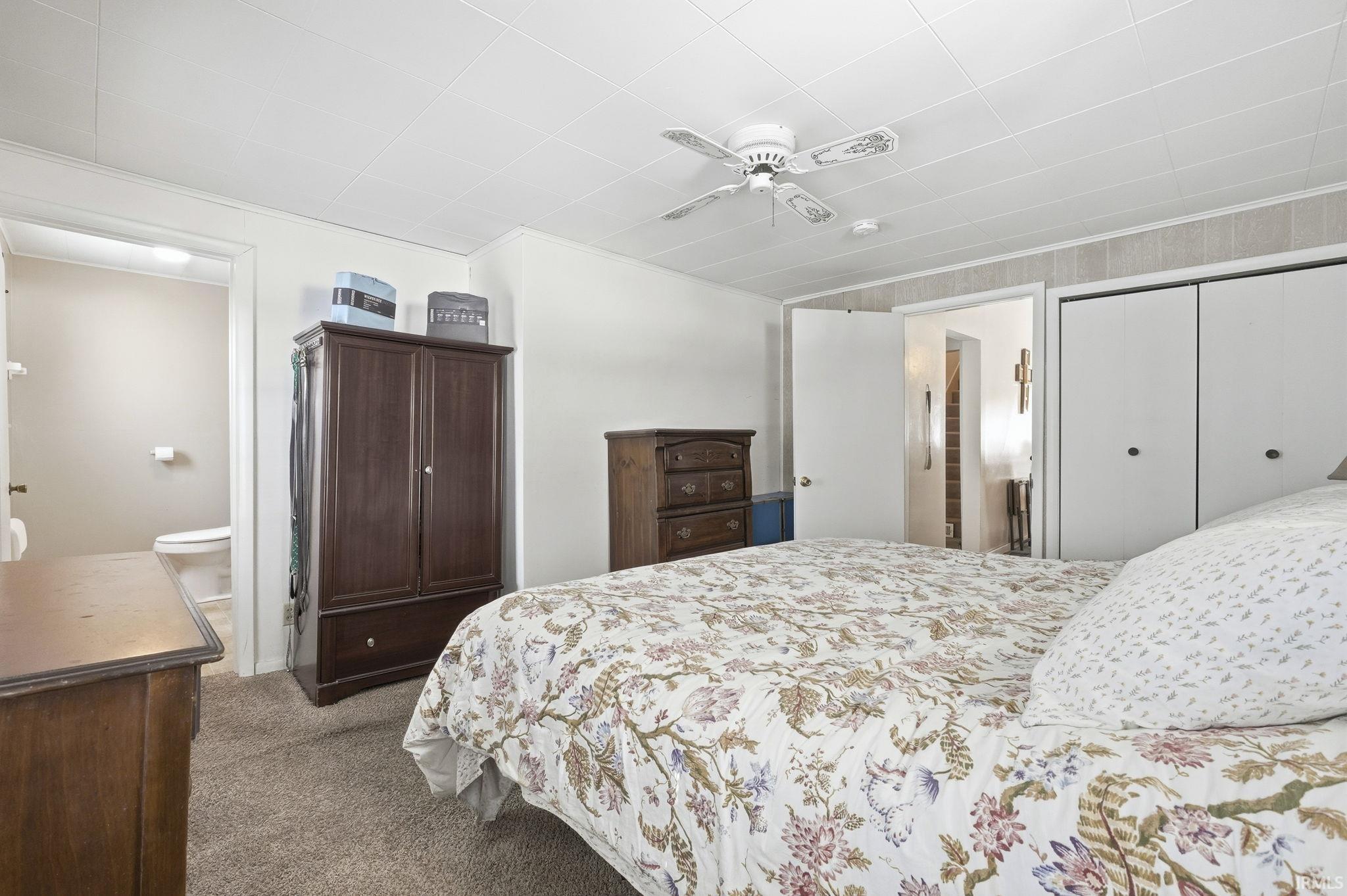Bedroom featuring dark colored carpet, connected bathroom, and a ceiling fan