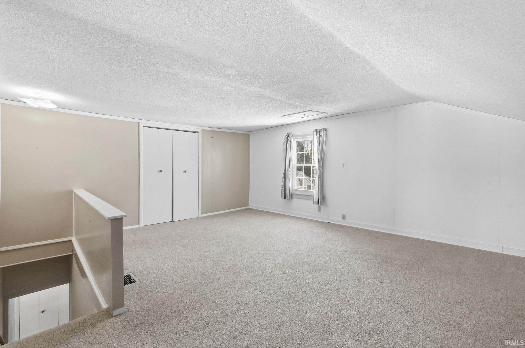 Below grade area featuring light colored carpet and a textured ceiling