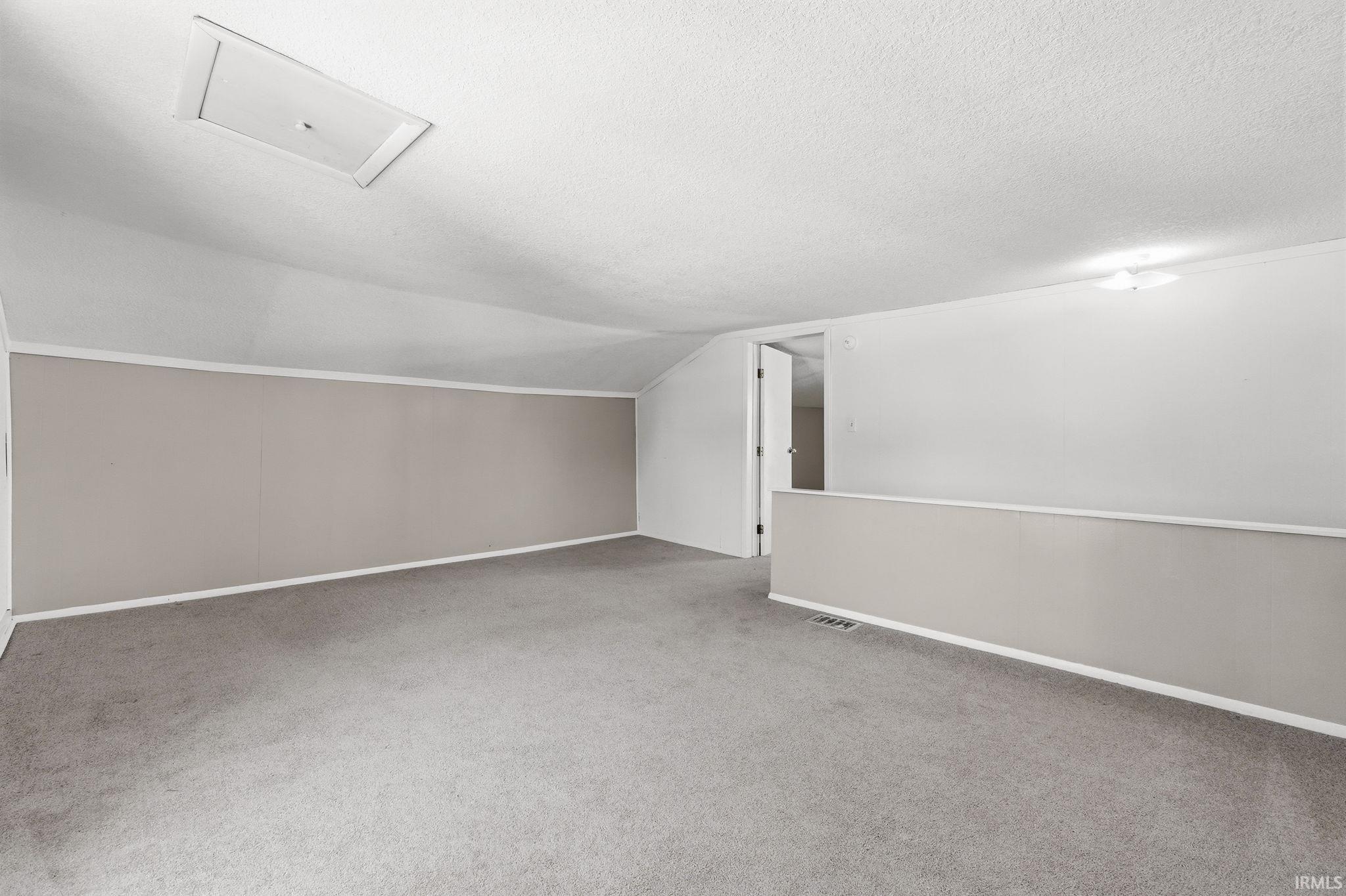 Bonus room featuring light colored carpet and attic access