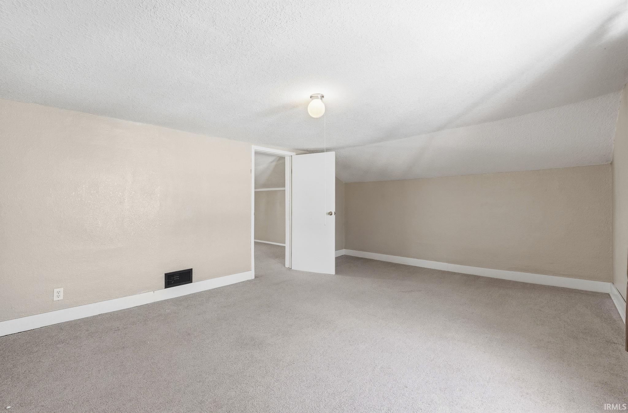 Additional living space with light colored carpet and baseboards
