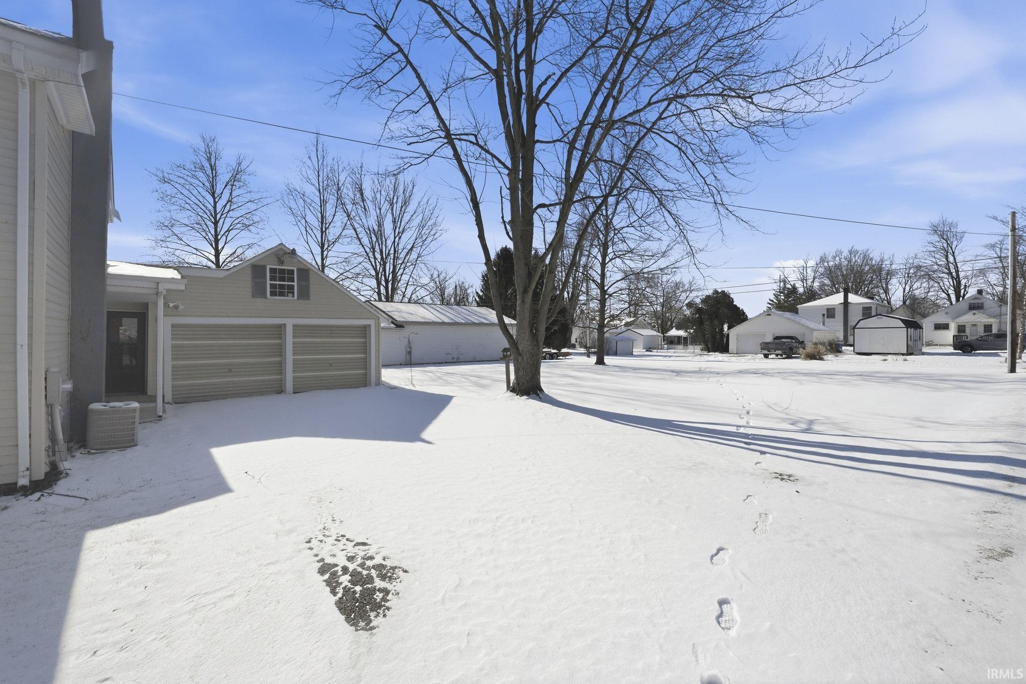 Yard covered in snow with a residential view, an outdoor structure, and a garage