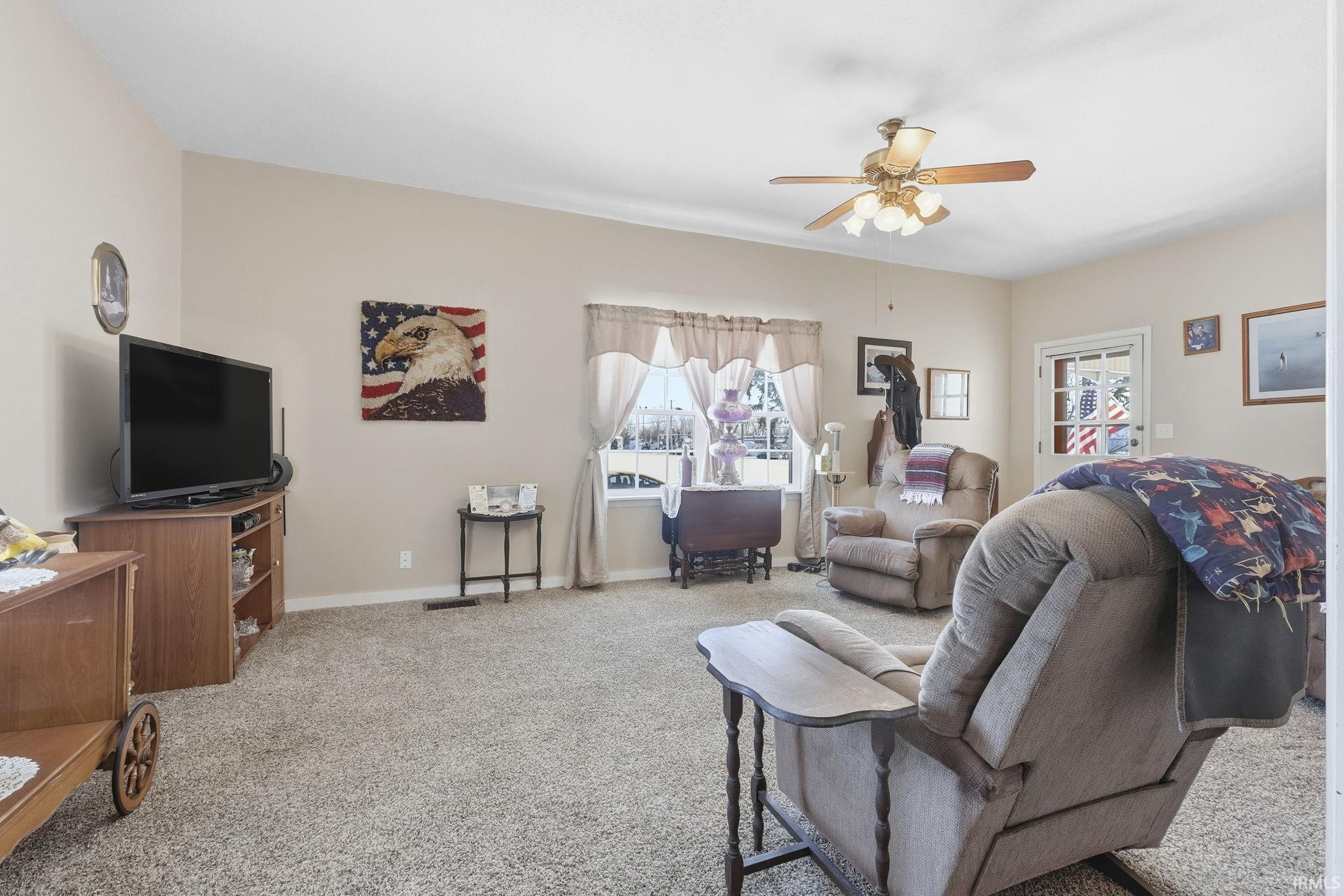 Carpeted living room with ceiling fan and baseboards