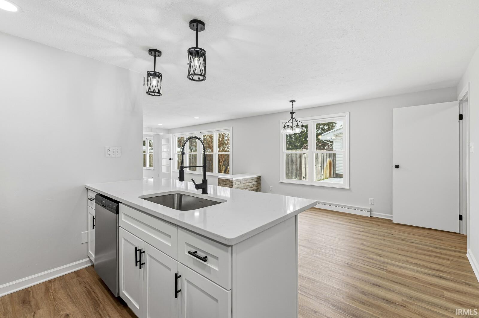Kitchen with white cabinetry, a peninsula, light wood finished floors, hanging light fixtures, and recessed lighting