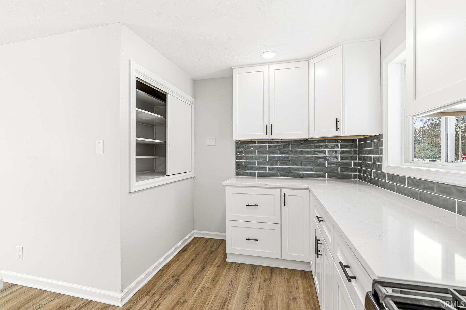Kitchen with white cabinetry, light wood-style floors, stainless steel range oven, light stone countertops, and recessed lighting