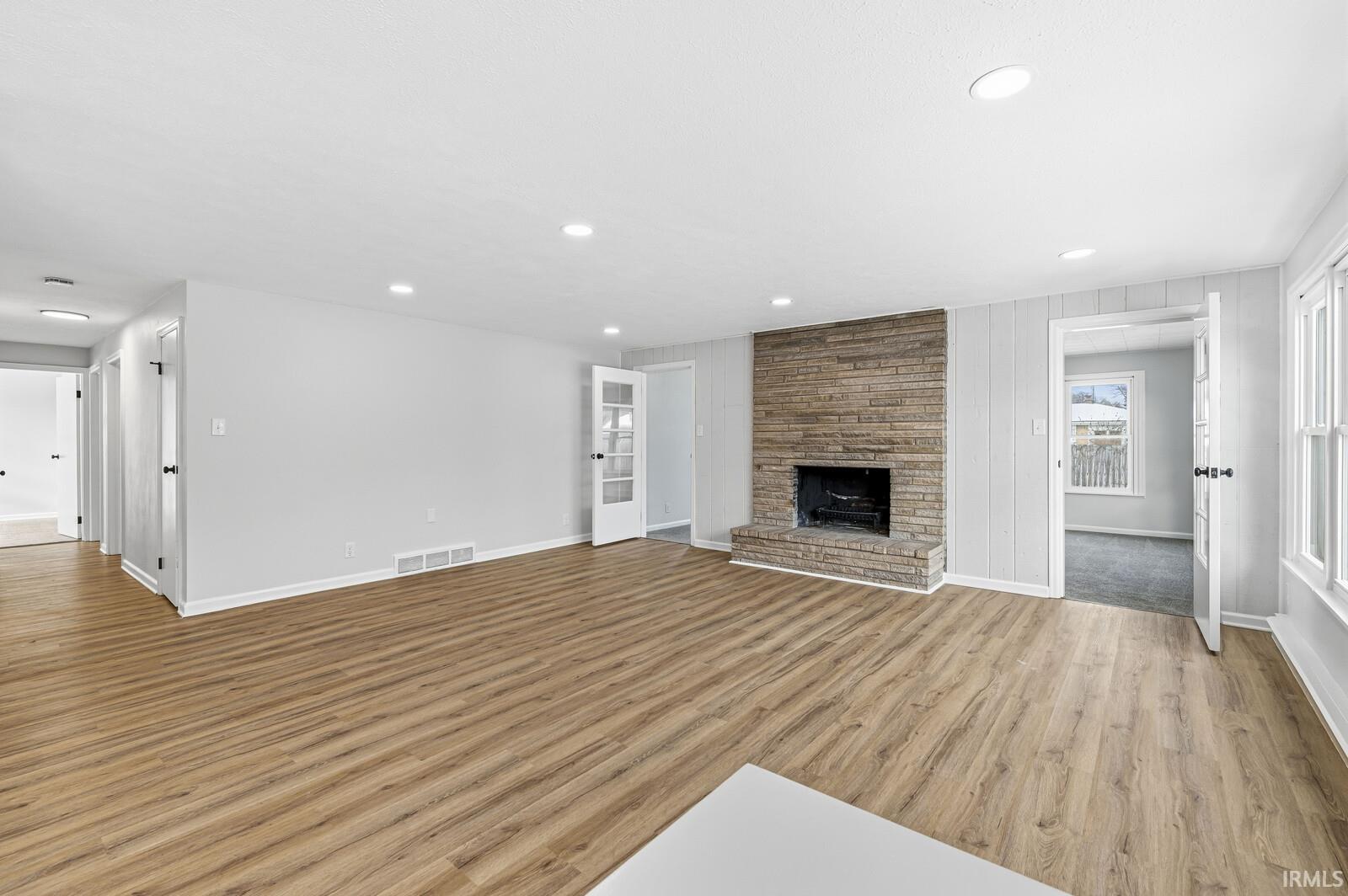 Unfurnished living room with recessed lighting, a stone fireplace, and light wood-type flooring