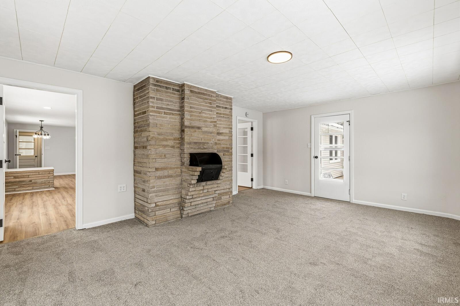 Unfurnished living room with carpet floors and a chandelier