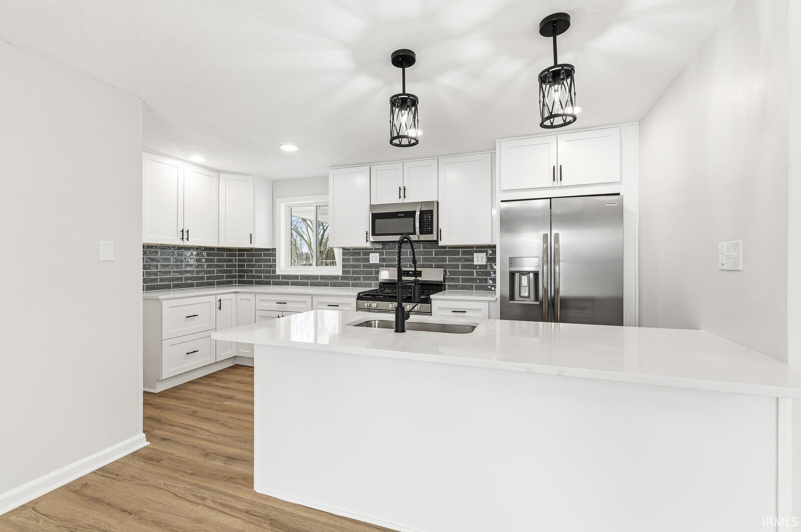 Kitchen featuring white cabinetry, stainless steel appliances, light stone counters, backsplash, and recessed lighting