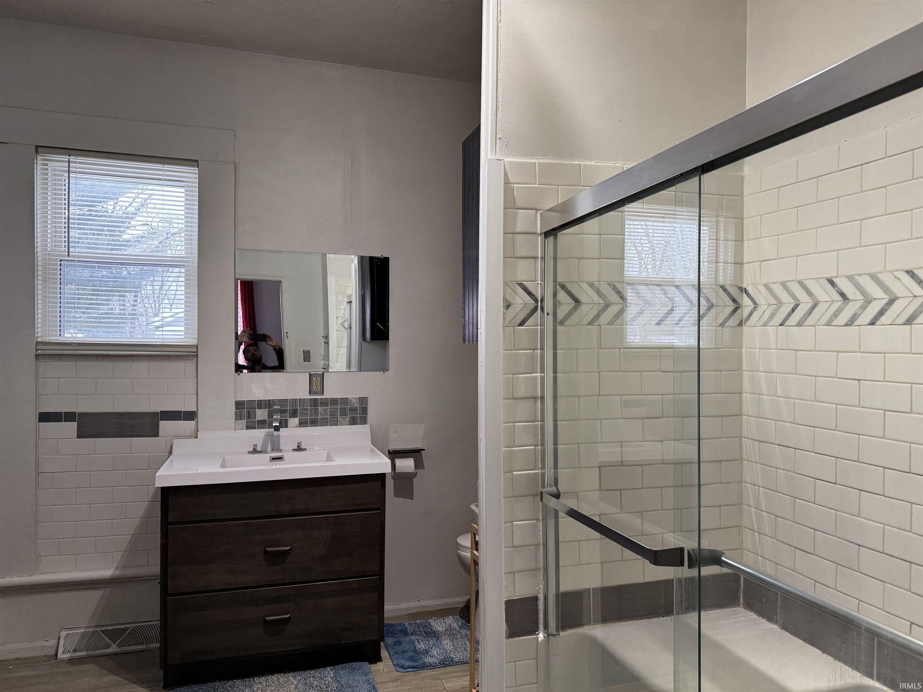 Full bath featuring vanity, bath / shower combo with glass door, and tasteful backsplash