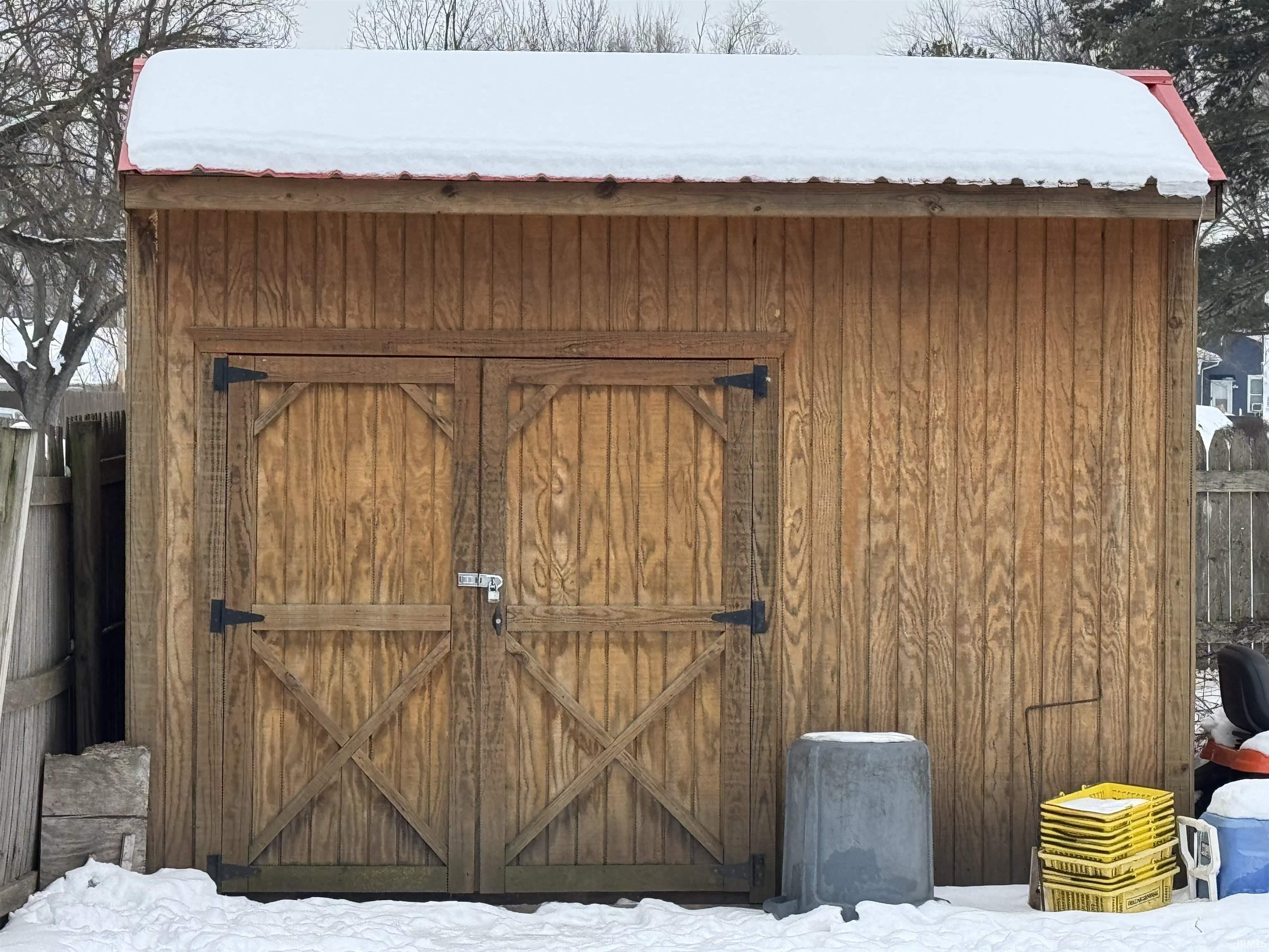 Snow covered structure featuring a storage shed