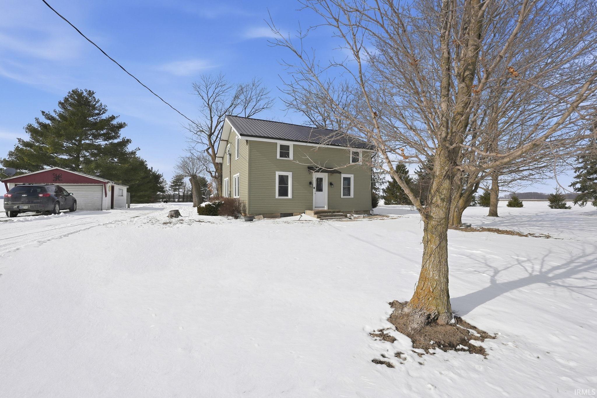 View of snow covered exterior with an outbuilding and a metal roof