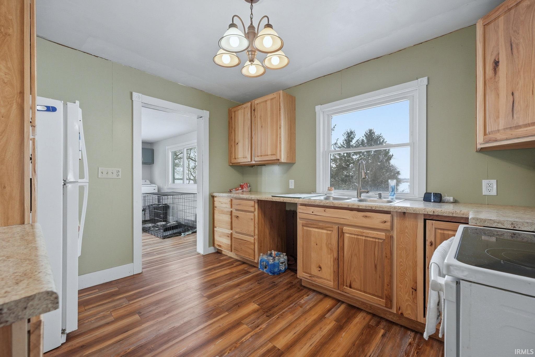 Kitchen featuring white appliances, light countertops, dark wood-type flooring, and light wood finish cabinetry