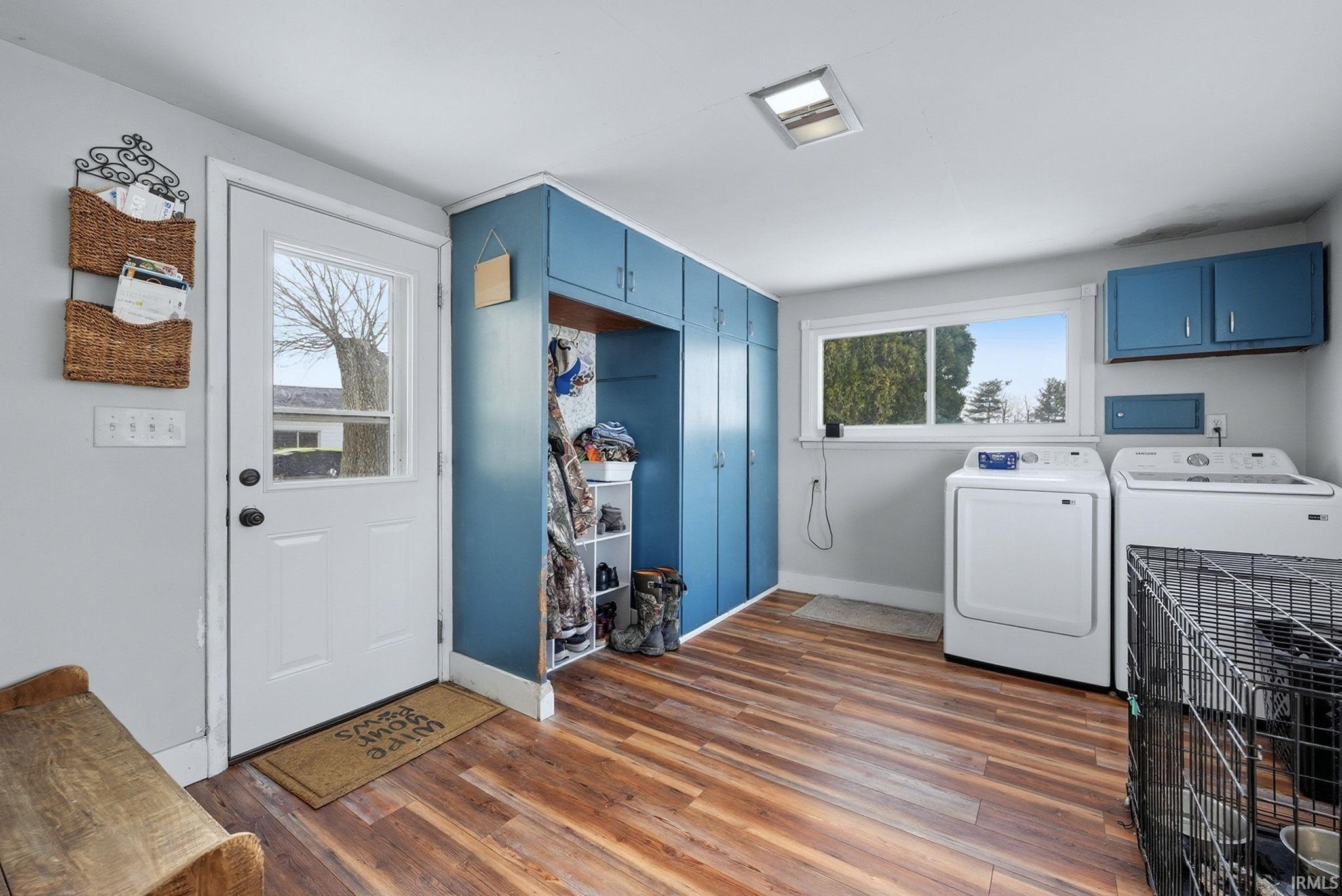 Laundry room featuring dark wood-type flooring, cabinet space, independent washer and dryer, and healthy amount of natural light