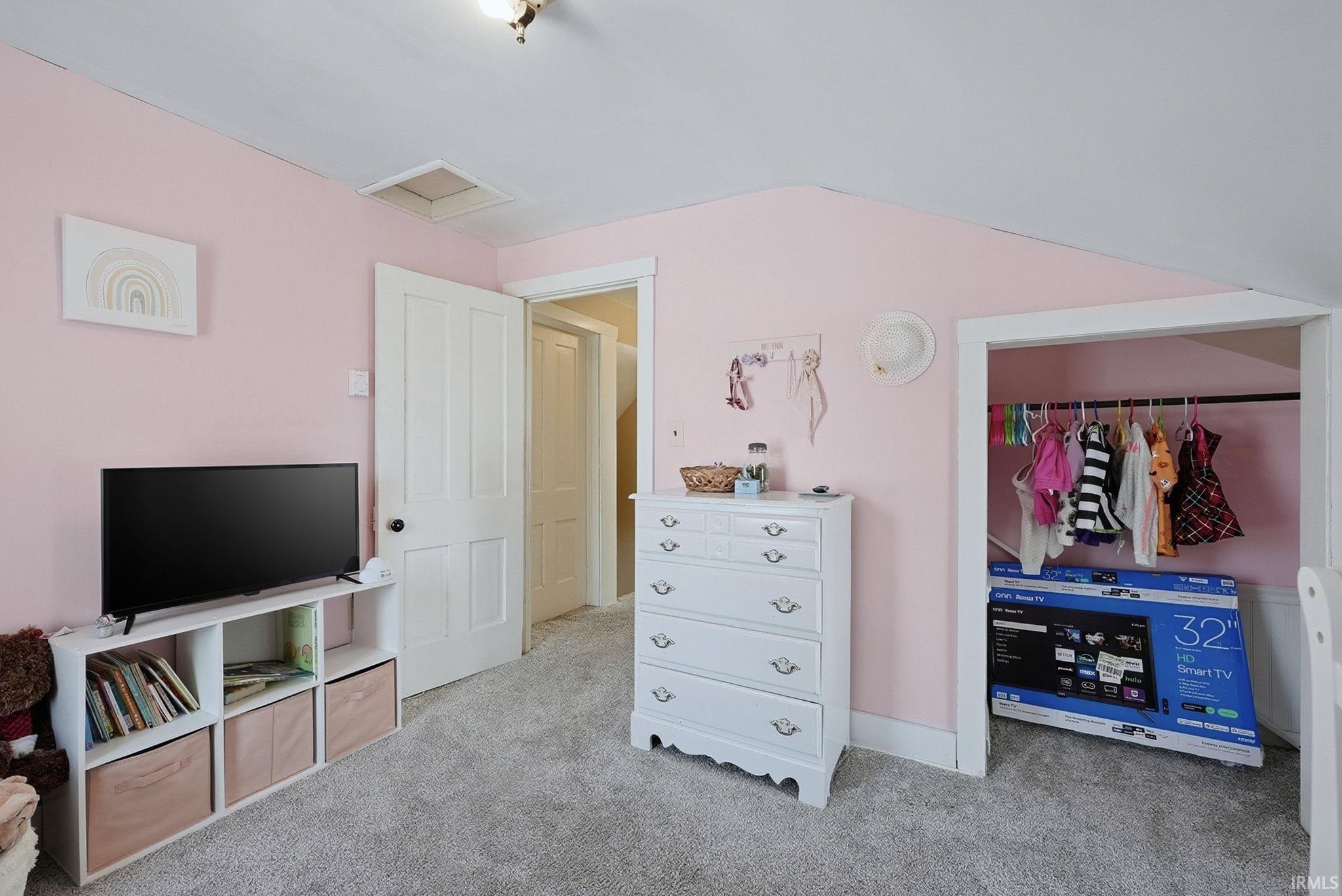 Bedroom with a closet, light carpet, and lofted ceiling