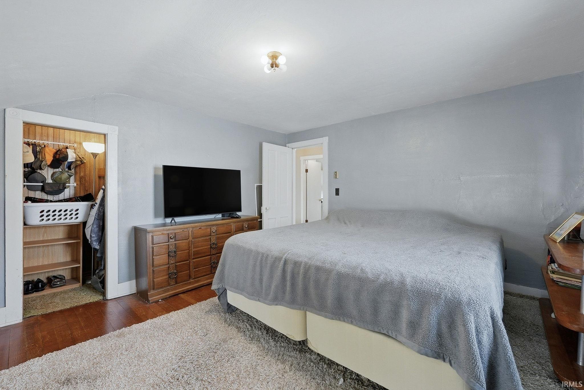 Bedroom featuring dark wood-style flooring and vaulted ceiling