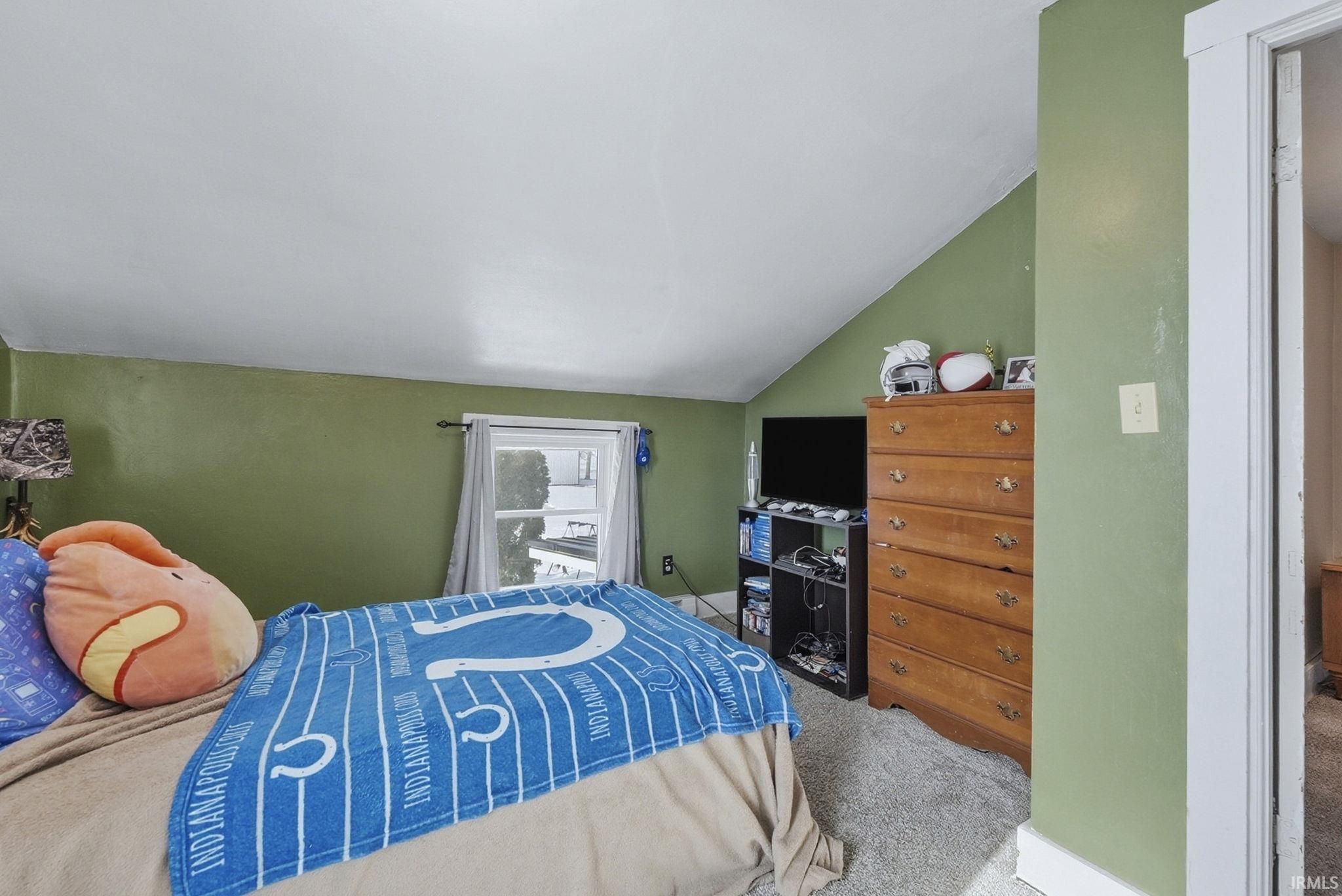 Carpeted bedroom featuring lofted ceiling