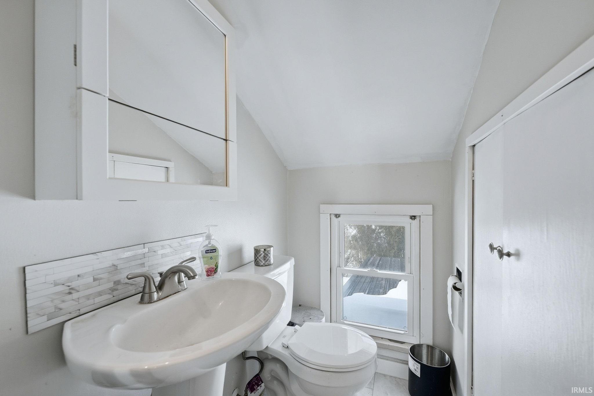 Bathroom with lofted ceiling and decorative backsplash