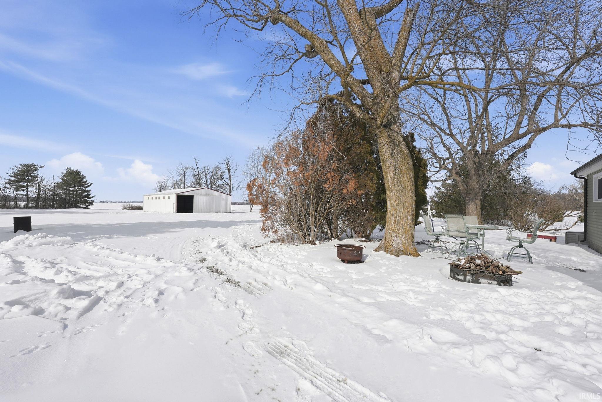 Yard covered in snow with an outdoor structure and an outbuilding