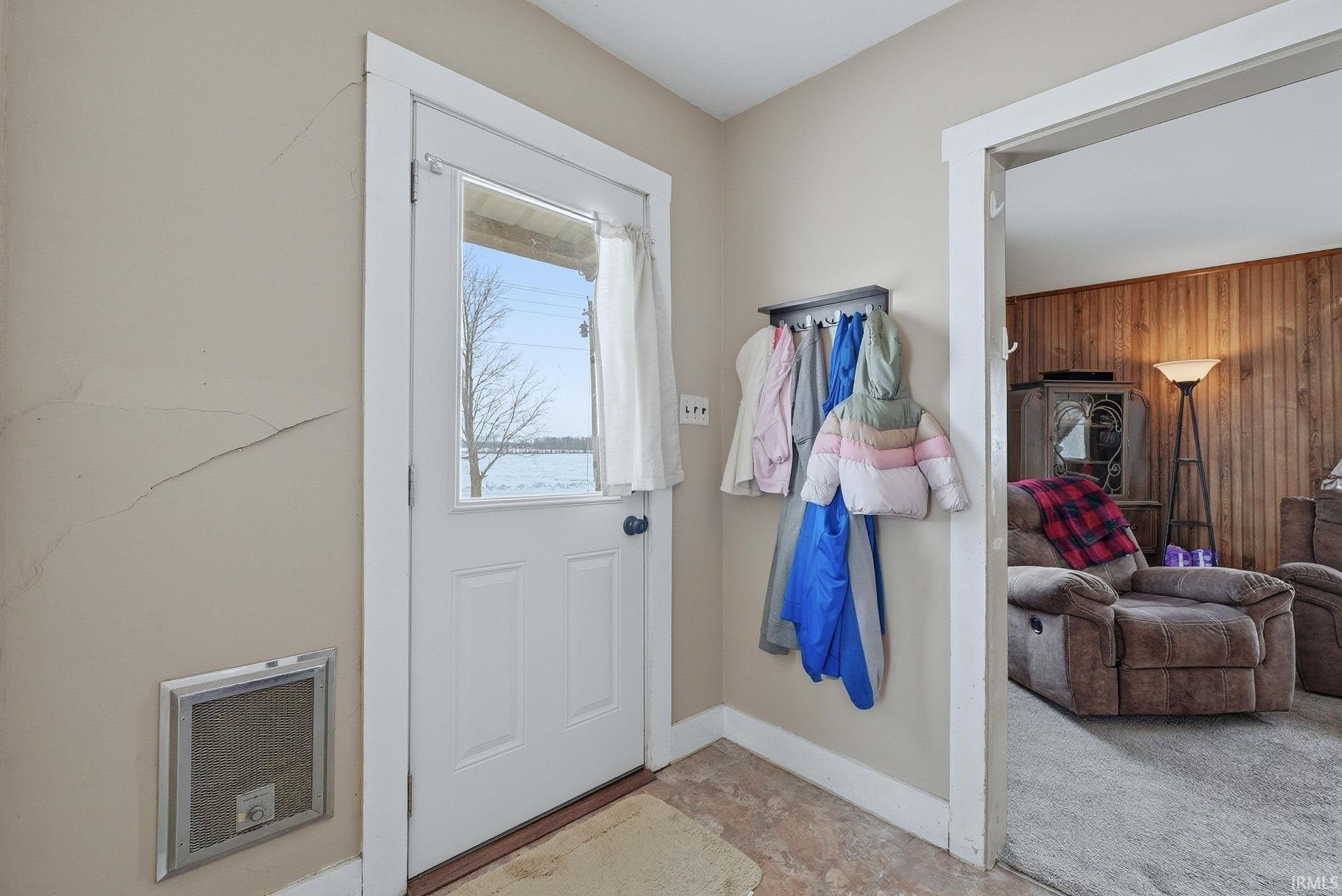 Doorway to outside with heating unit and wood walls
