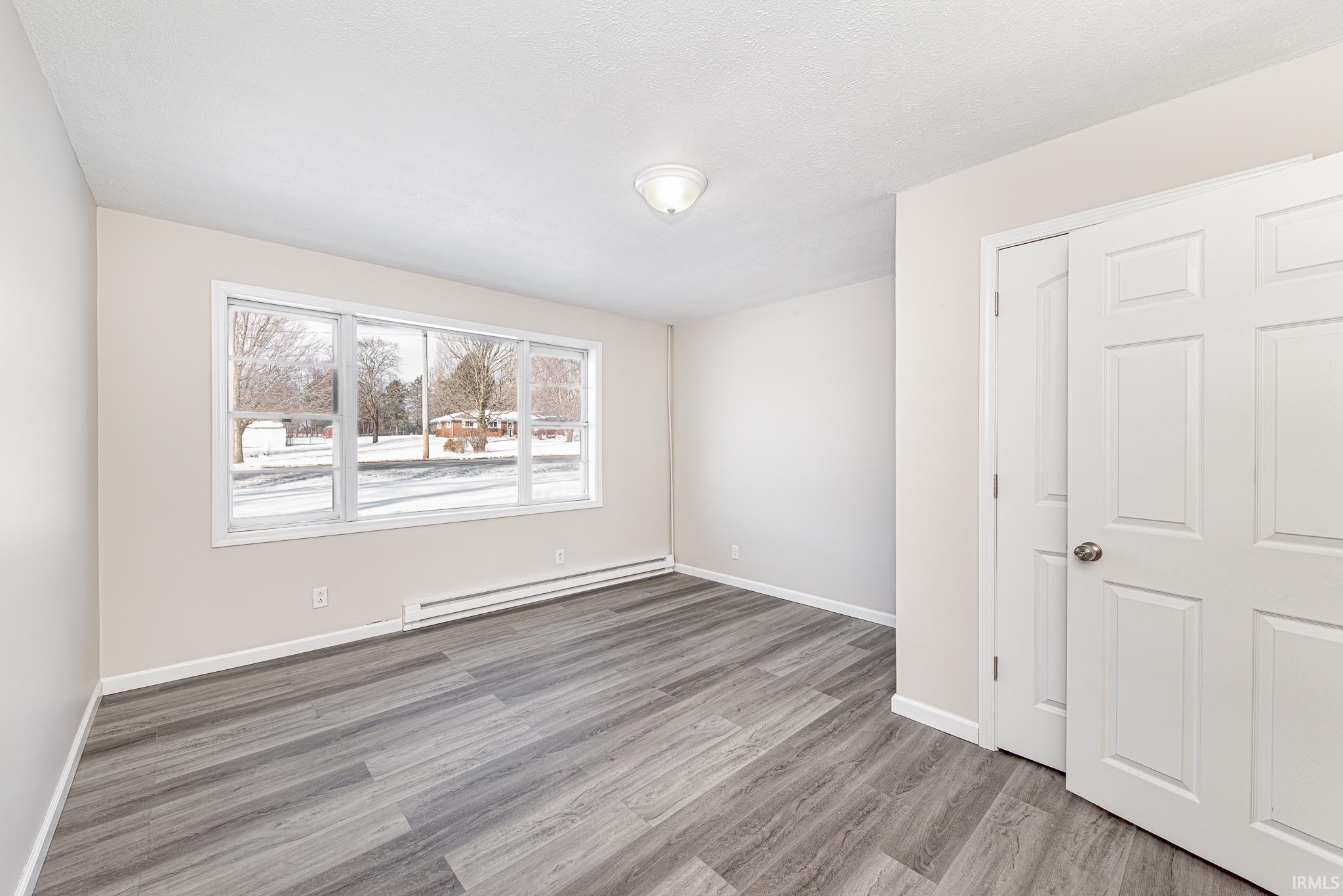 Empty room with a baseboard heating unit and light wood-style flooring