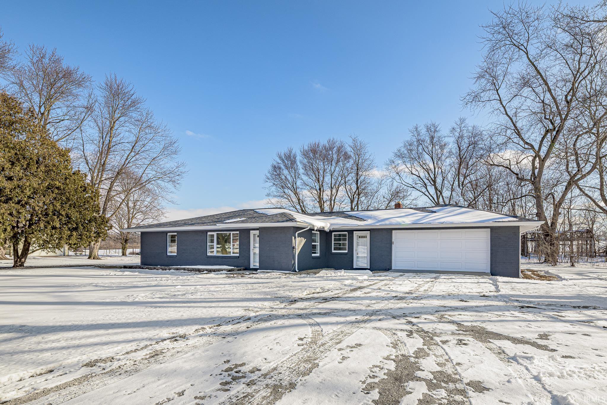 Ranch-style home featuring an attached garage, brick siding, and driveway
