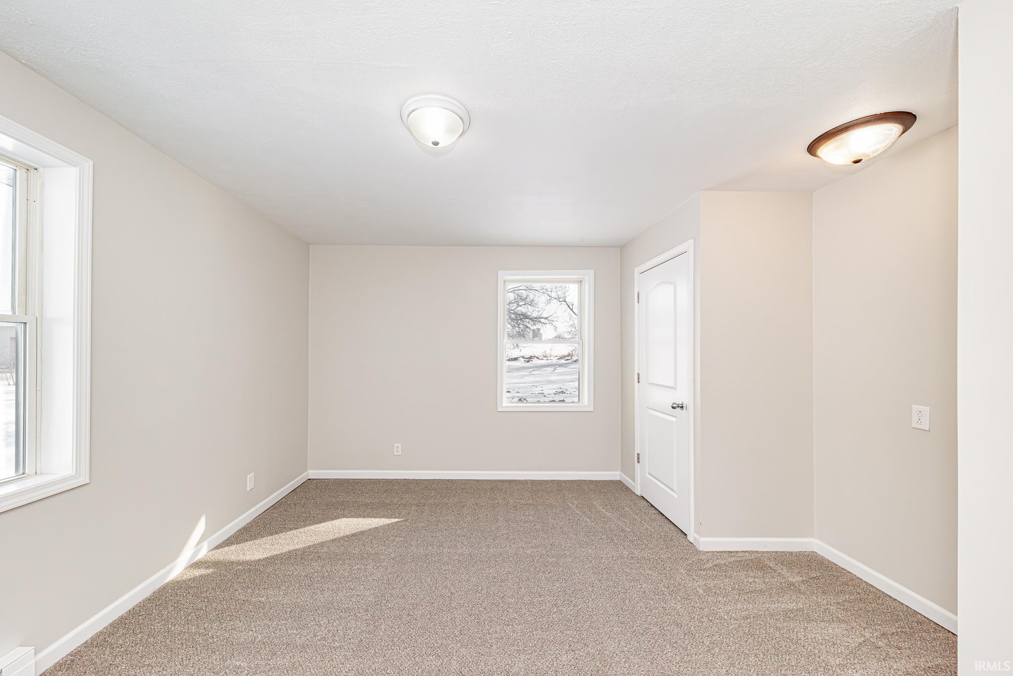 Empty room featuring baseboards and light colored carpet