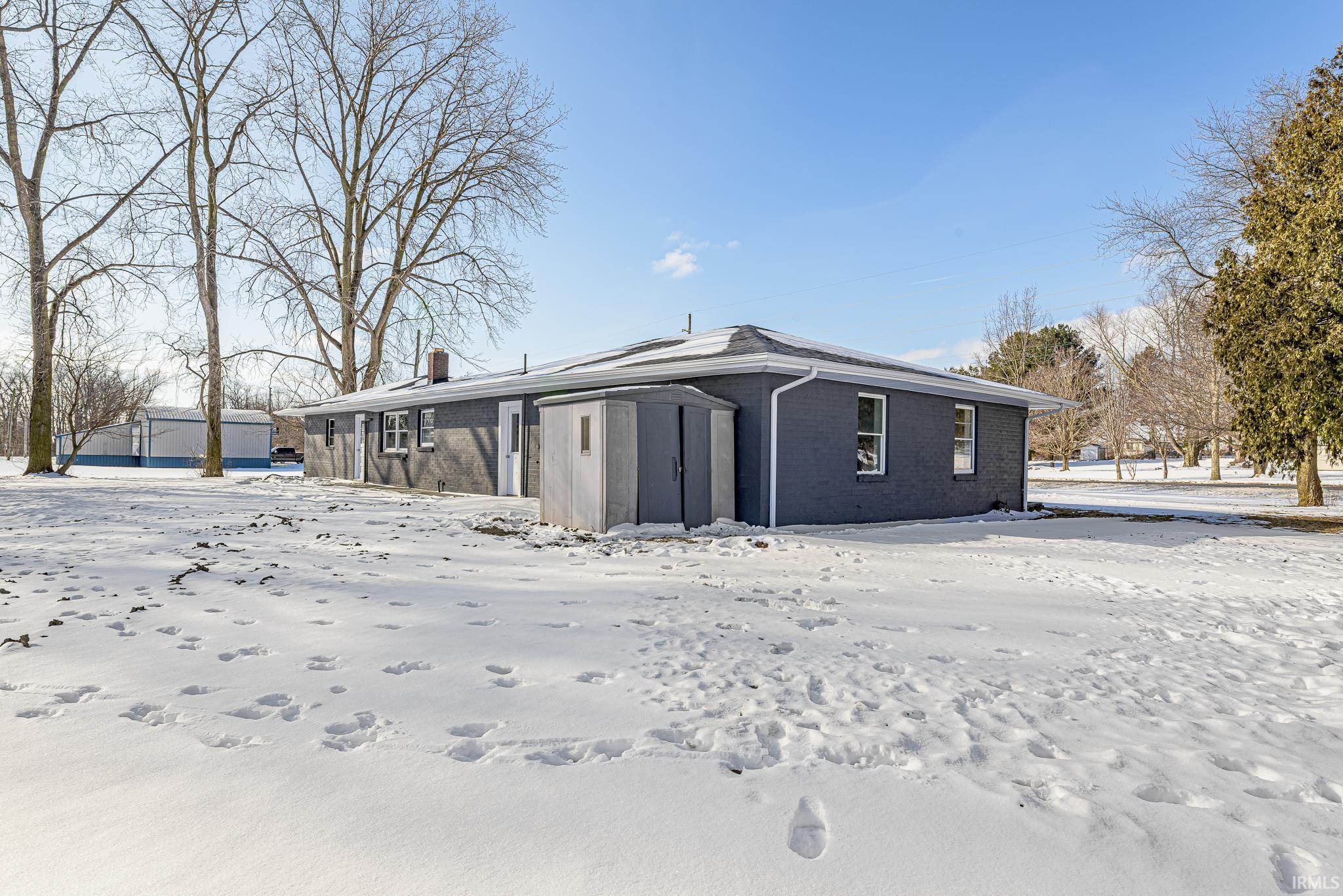 Snow covered property with brick siding and a chimney