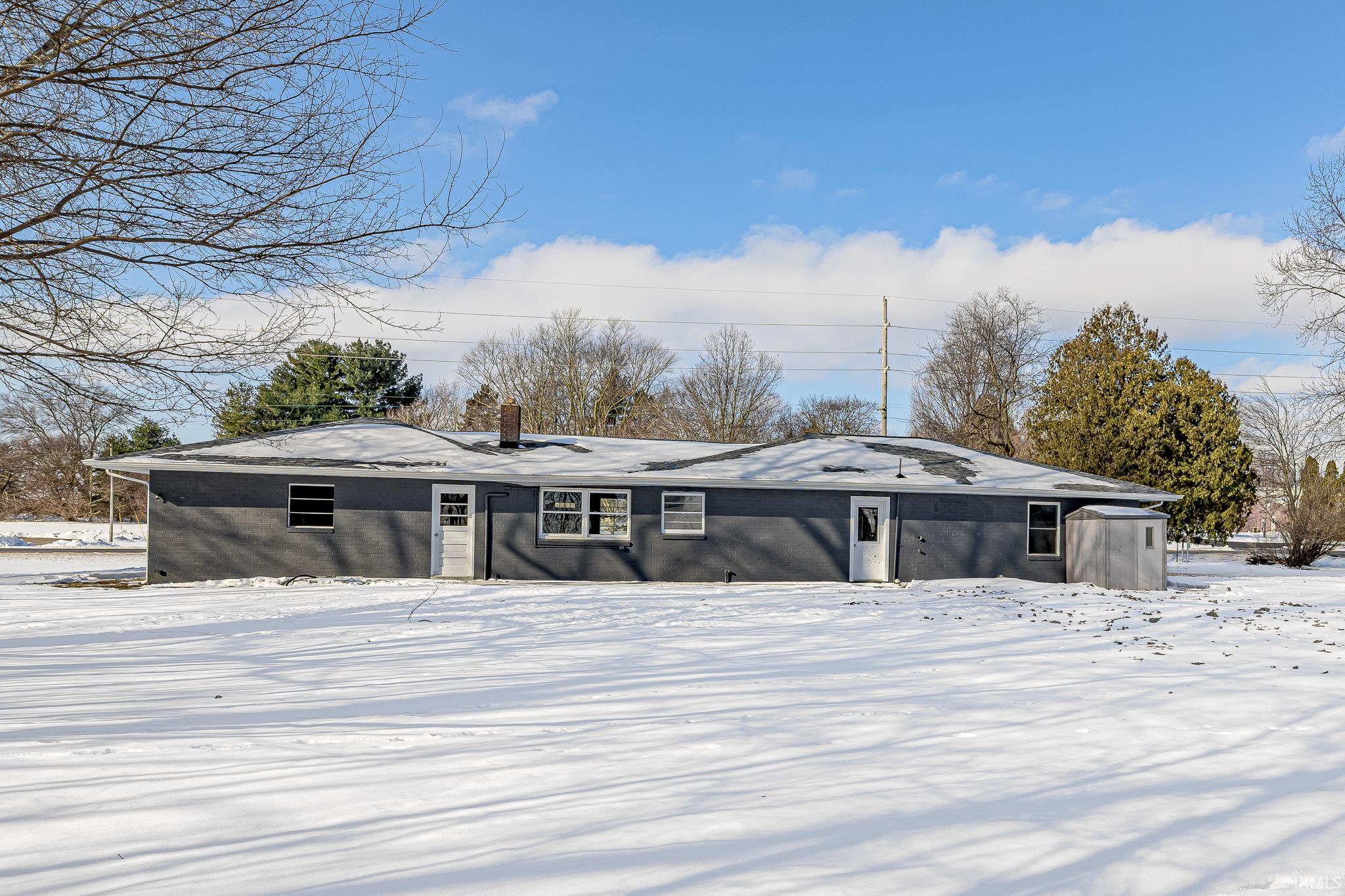 Snow covered house with a chimney and brick siding