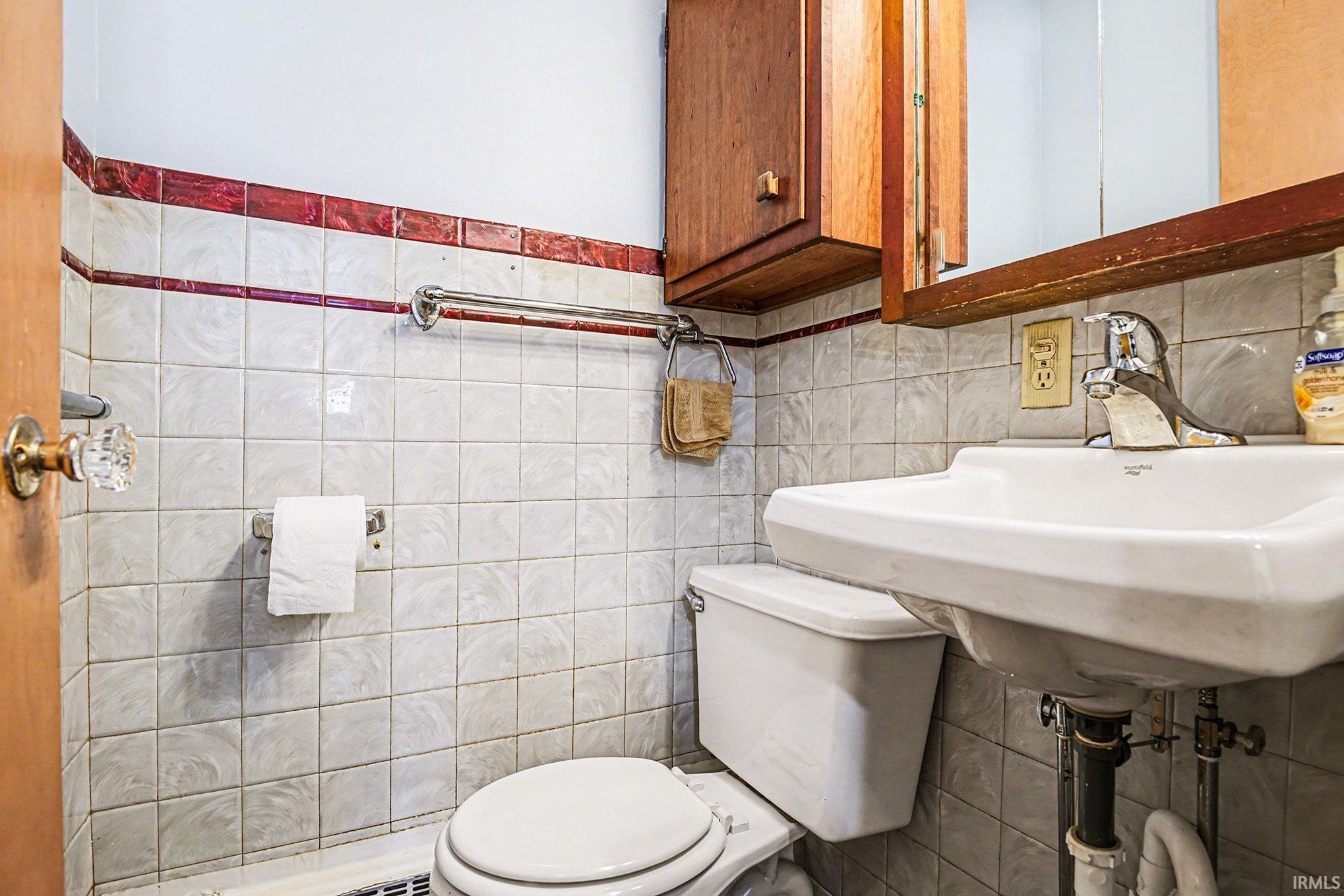 Bathroom featuring toilet and tile walls
