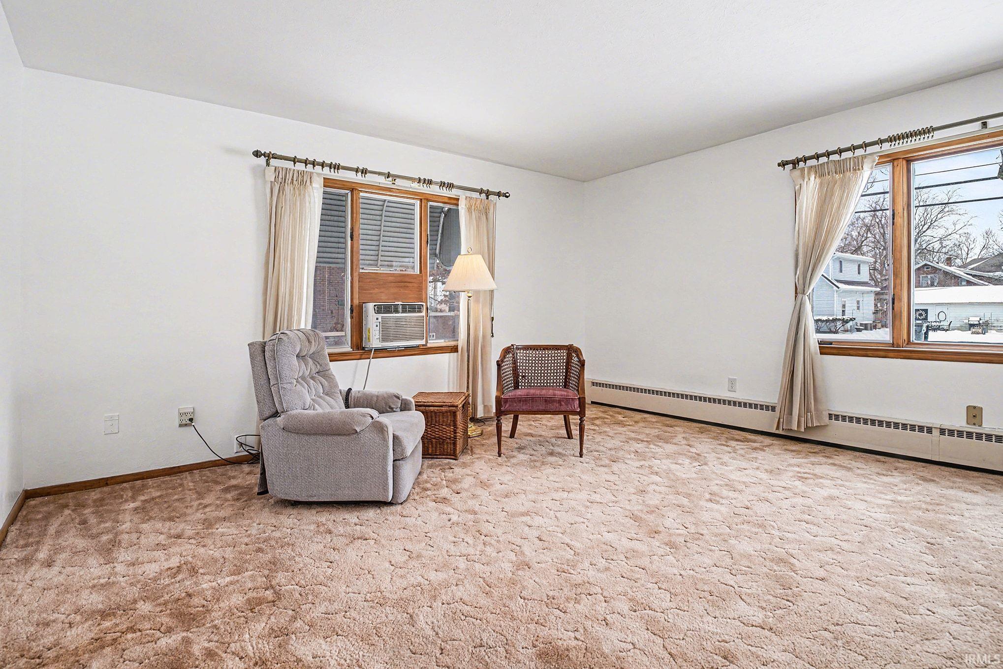 Living area featuring a baseboard radiator and light carpet