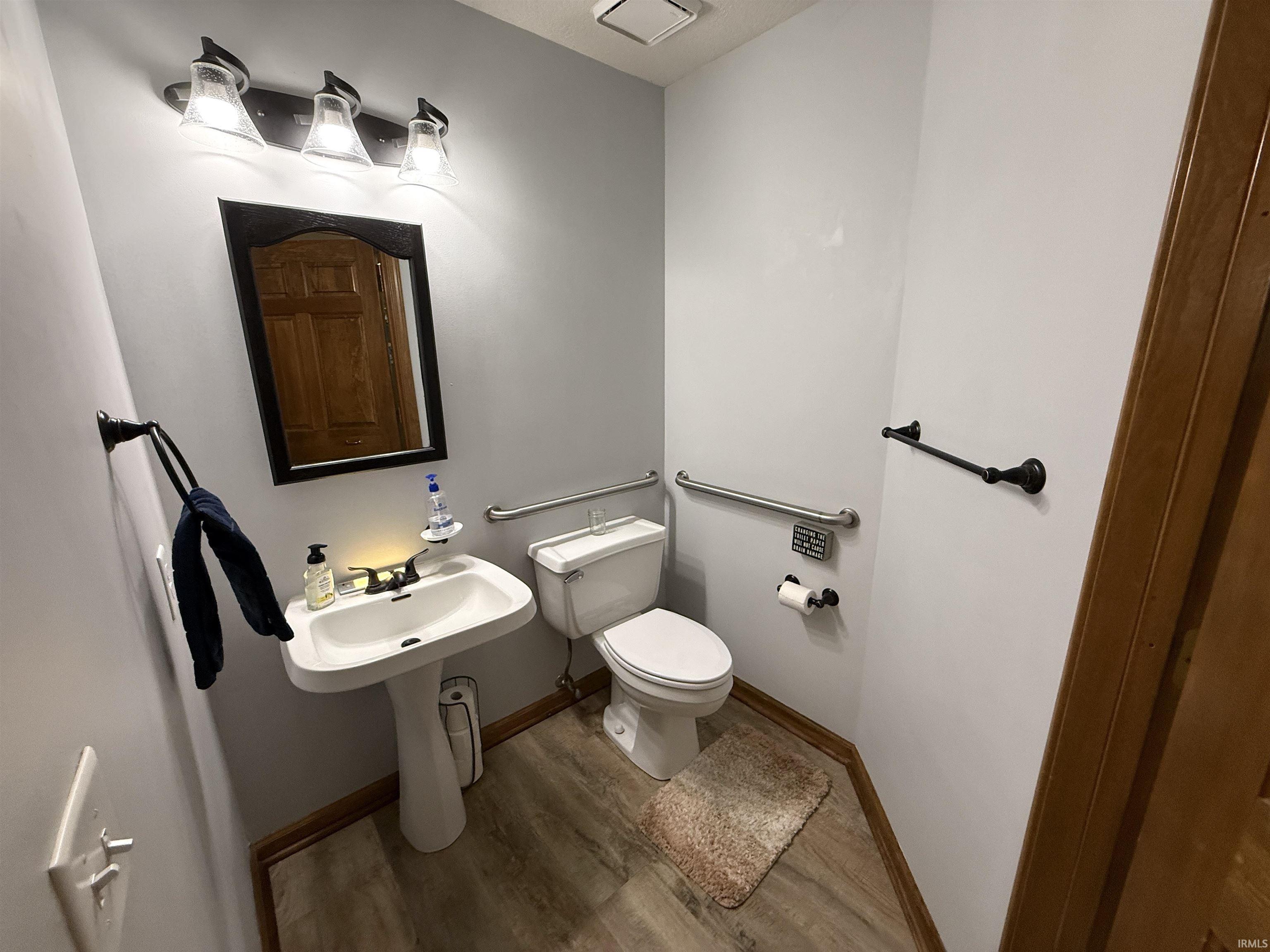 Half bathroom with wood finished floors and toilet