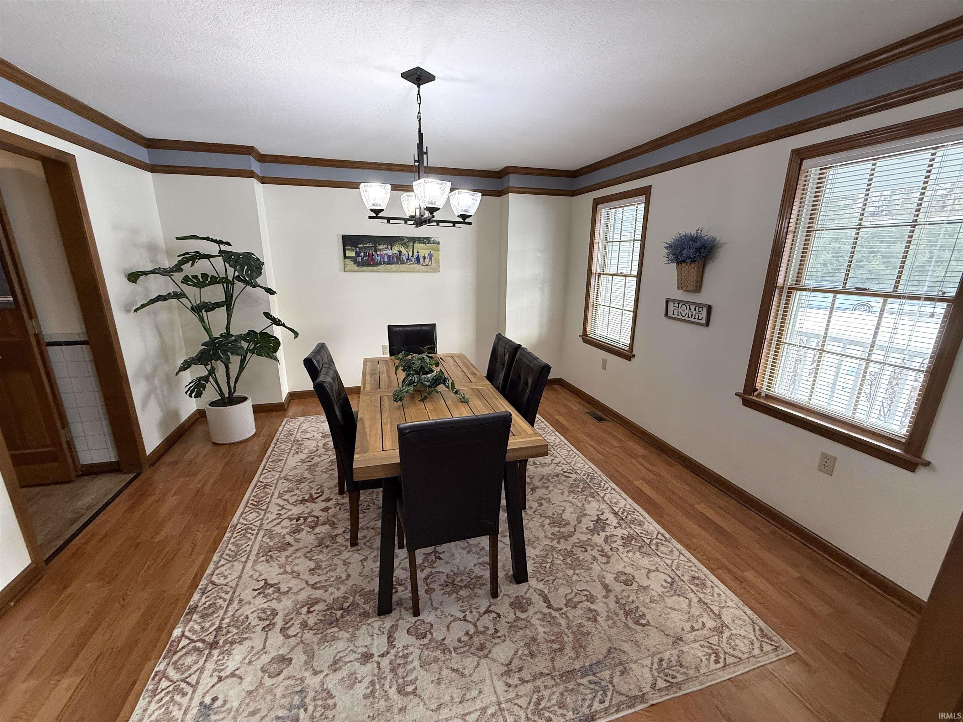 Dining space with ornamental molding, suspended lighting, and light wood finished floors