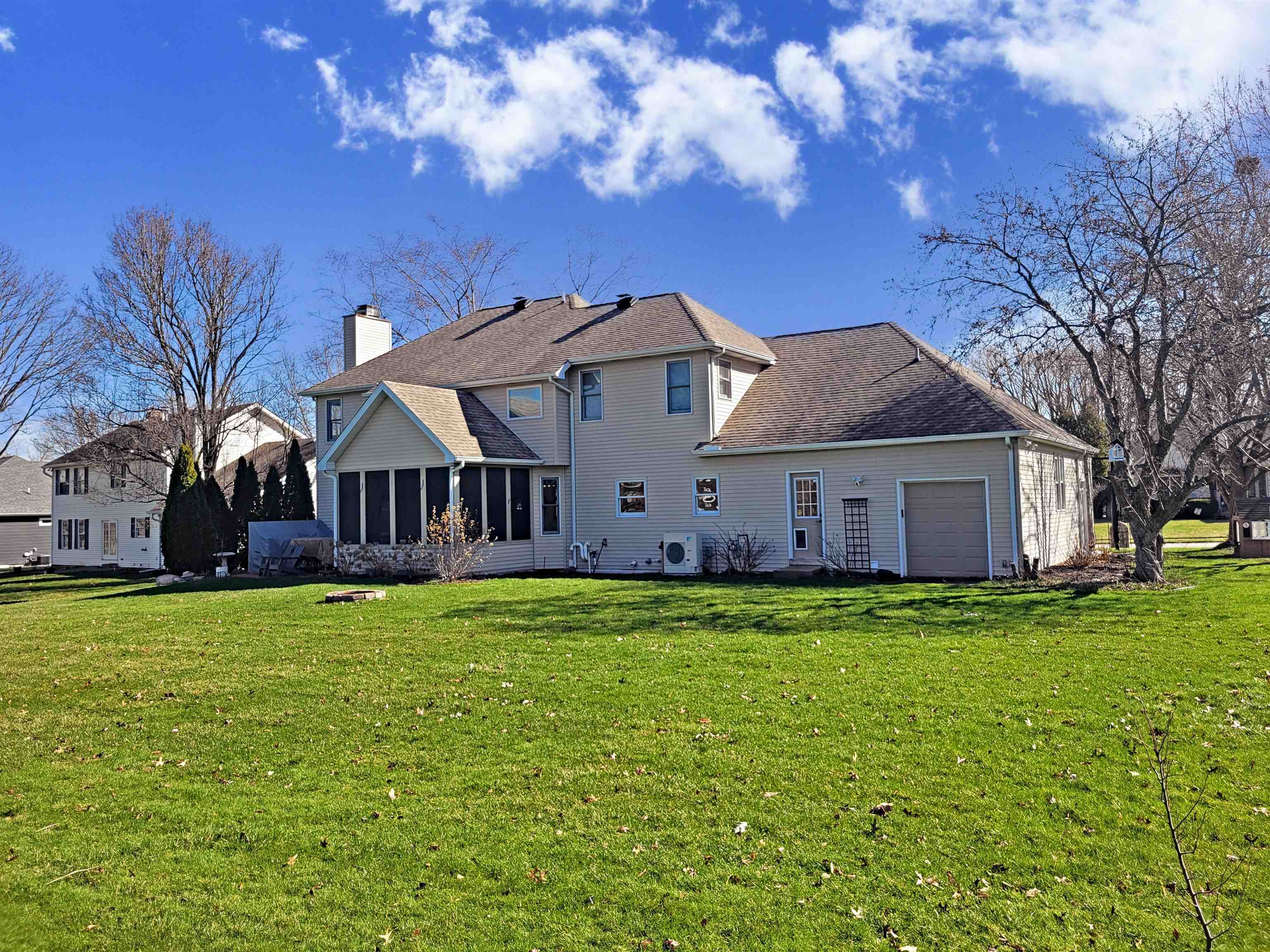 Back of house featuring a sunroom, an attached garage, a lawn, and roof with shingles