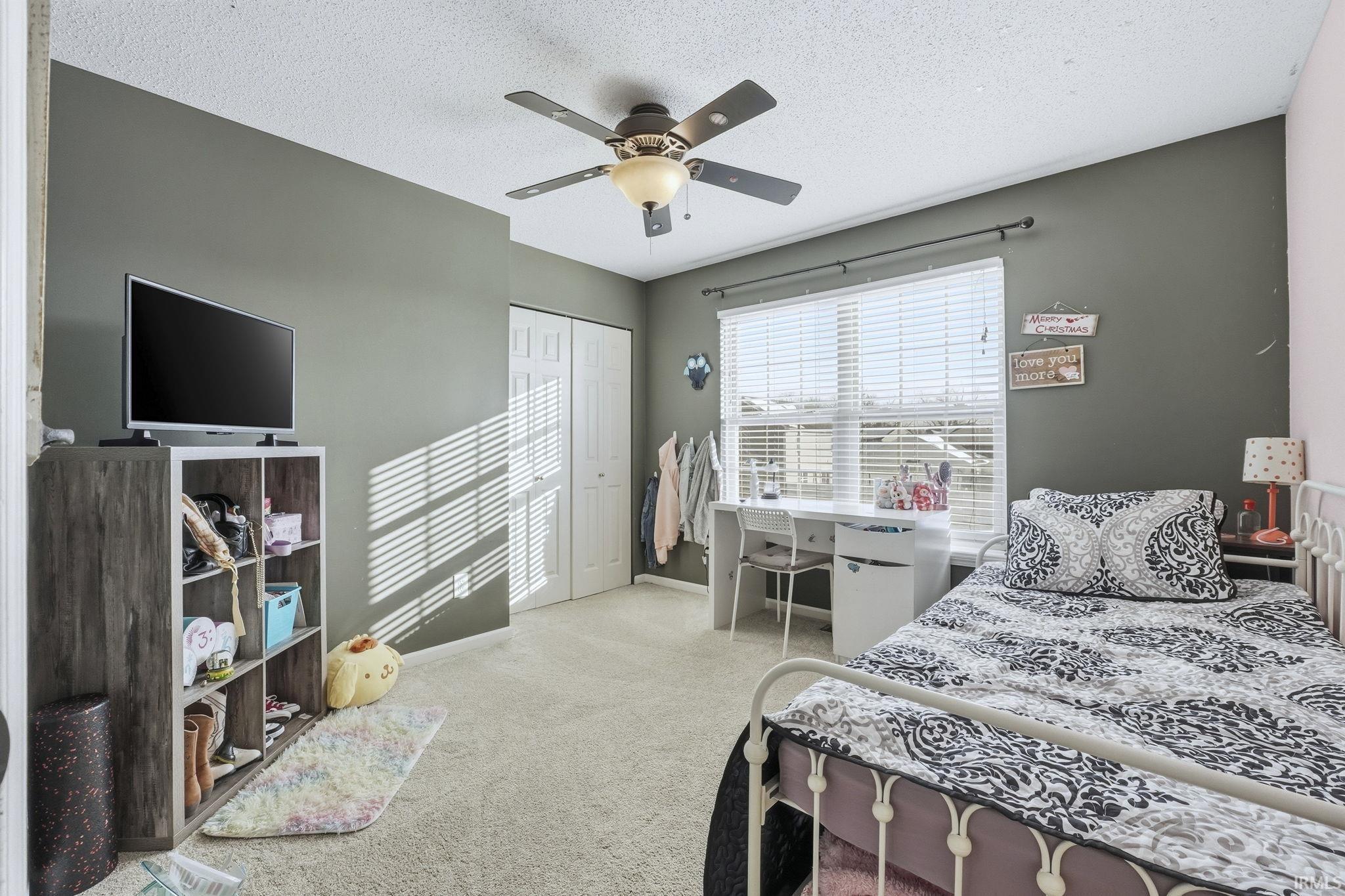 Bedroom with a ceiling fan, light carpet, a textured ceiling, and a closet