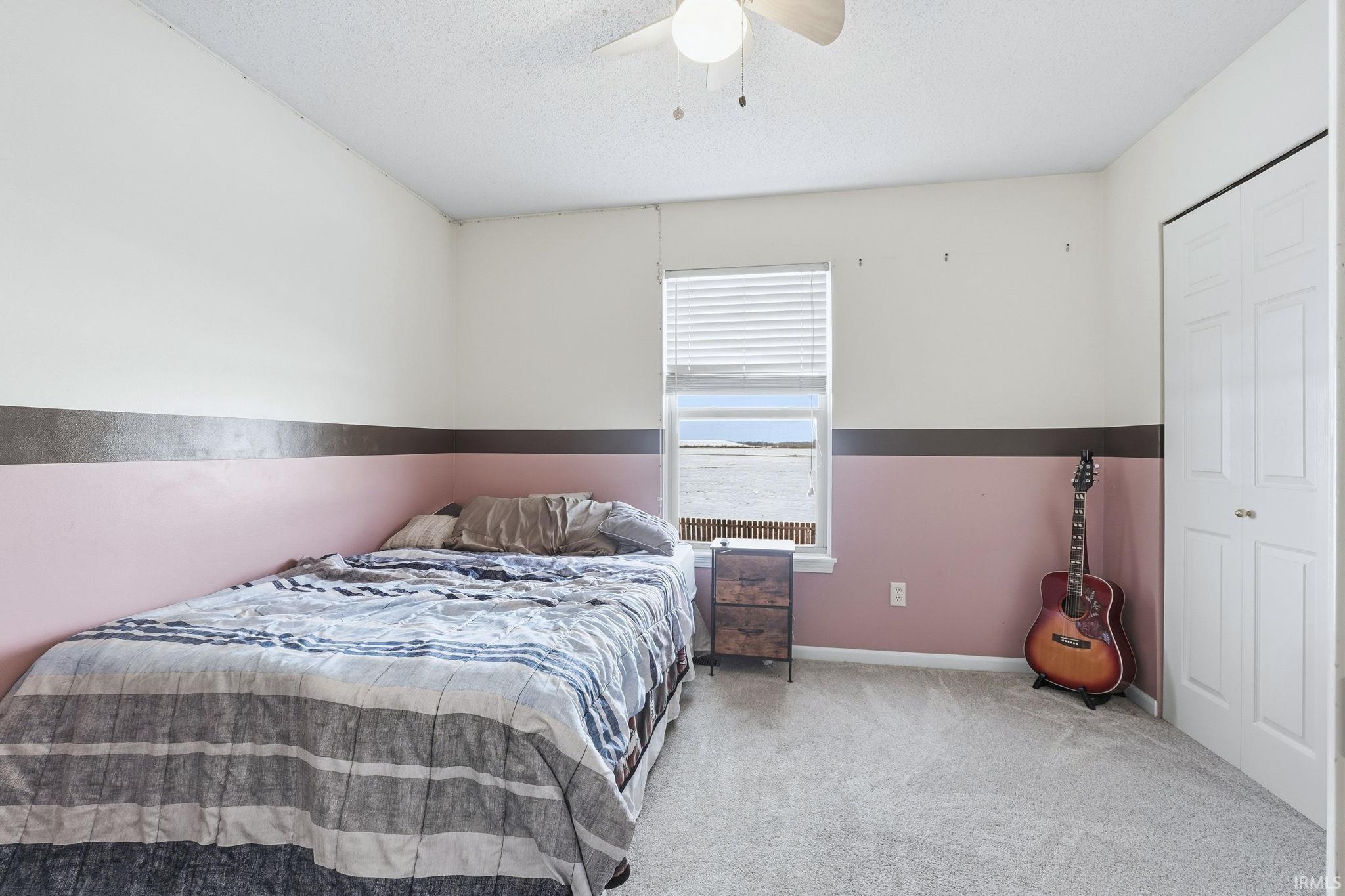 Carpeted bedroom with ceiling fan, a closet, and a textured ceiling