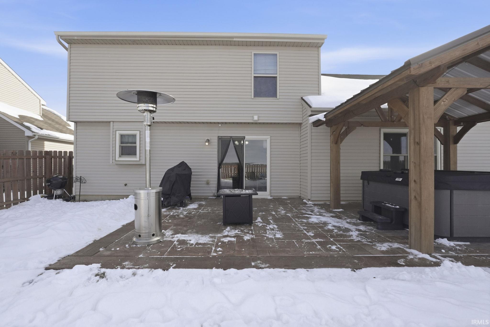 Snow covered house with a patio area and a hot tub