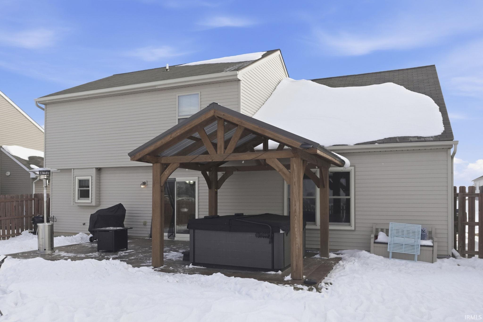 Snow covered house with a hot tub, a patio area, and a gazebo