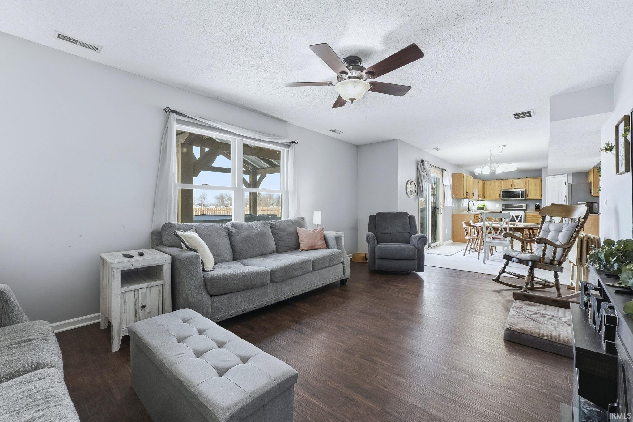 Living area featuring dark wood-style floors, ceiling fan, and a textured ceiling